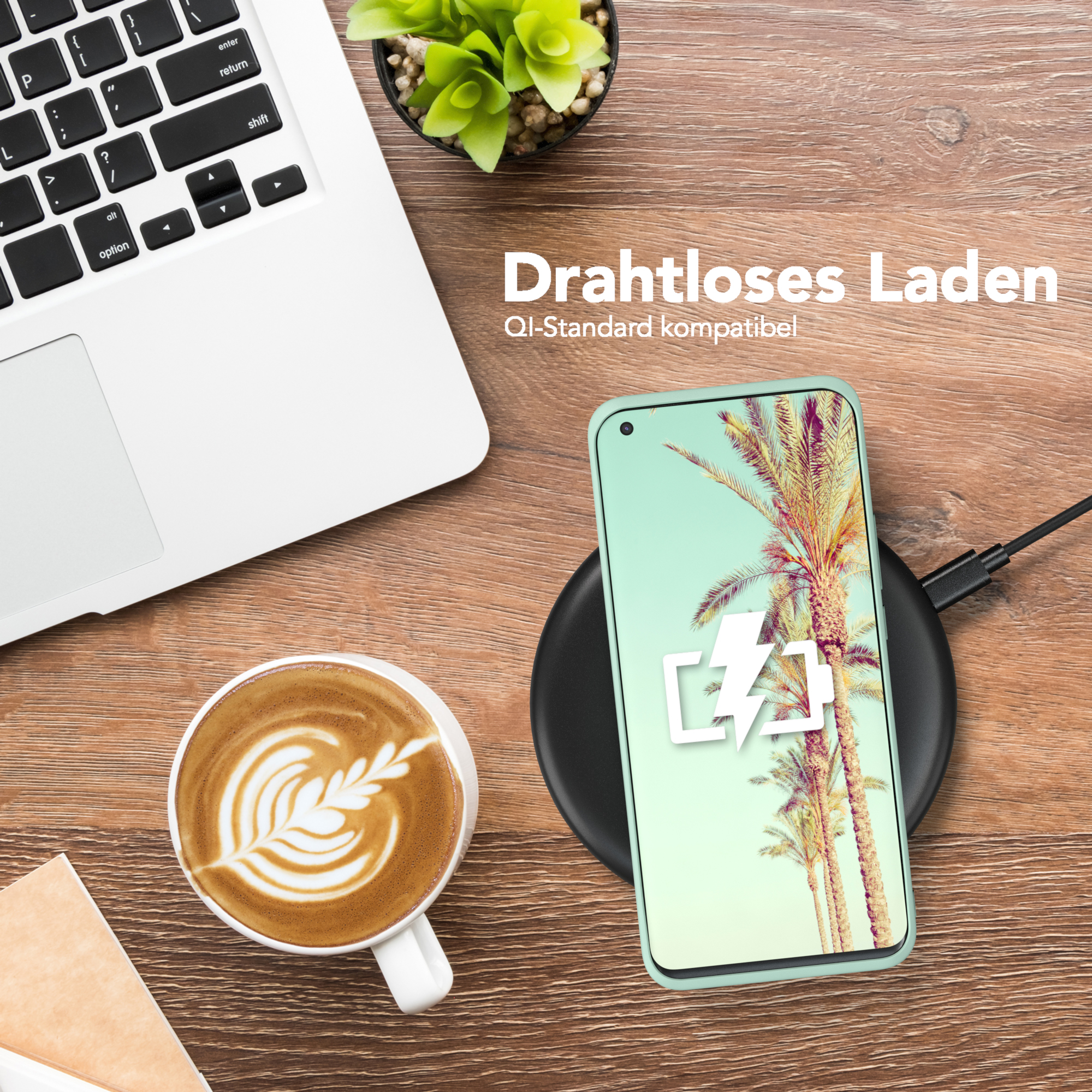Telefon mit Hülle wird kabellos geladen. Laptop, Kaffee und Pflanze stehen auf dem Holztisch.