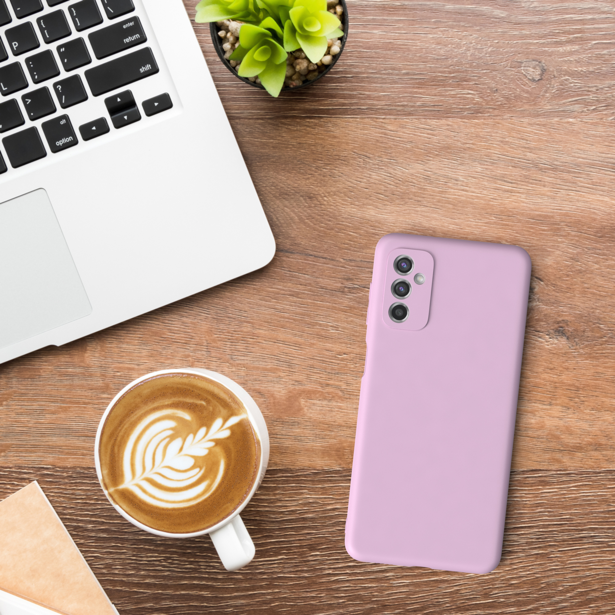 Laptop, Kaffee, pinke Handyhülle und Pflanze auf Holztisch.