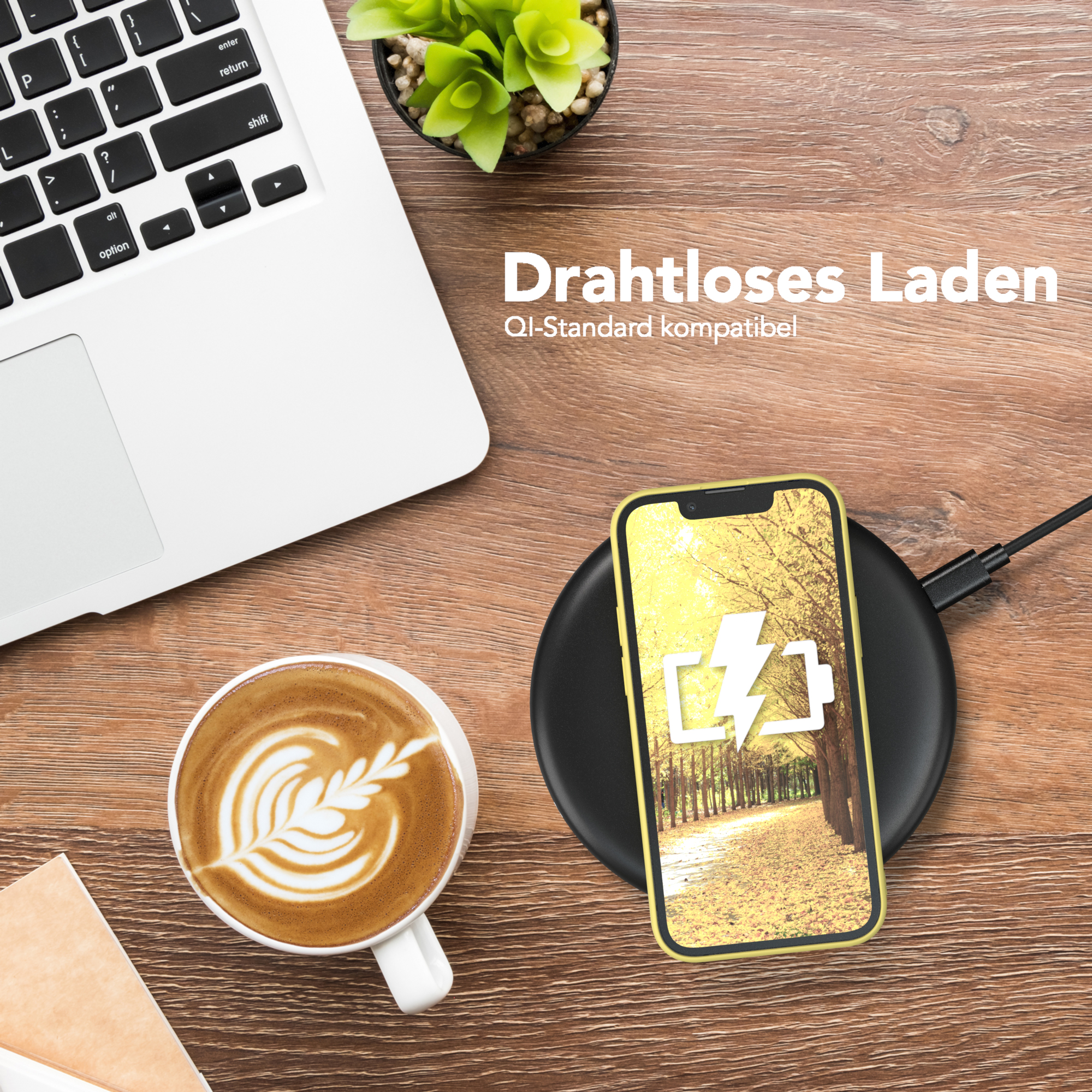 Laptop, Kaffee, Telefon wird geladen und eine Pflanze auf einem Holztisch.