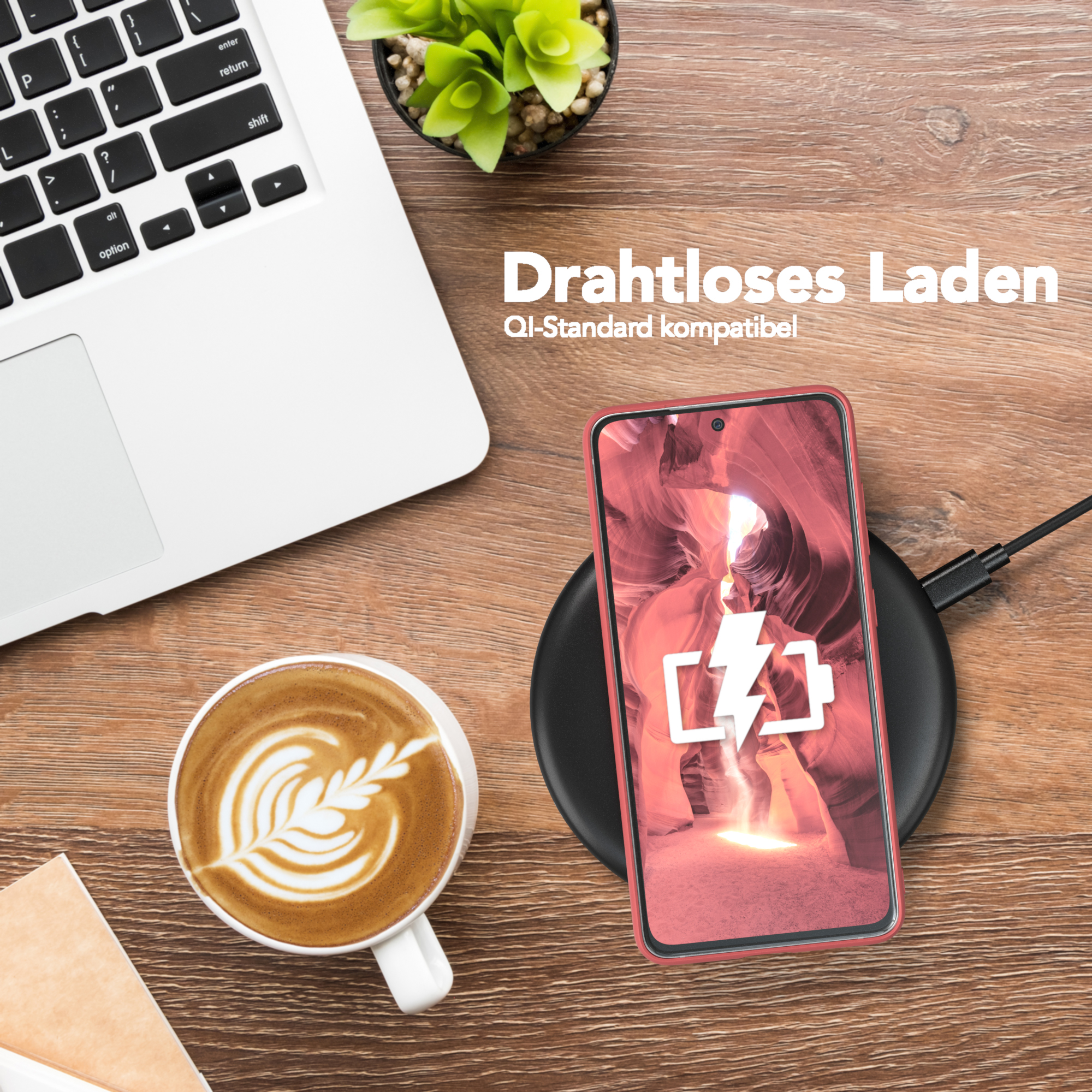 Ein Telefon, das auf einem kabellosen Ladegerät geladen wird, zusammen mit Laptop, Kaffeetasse und Pflanze.