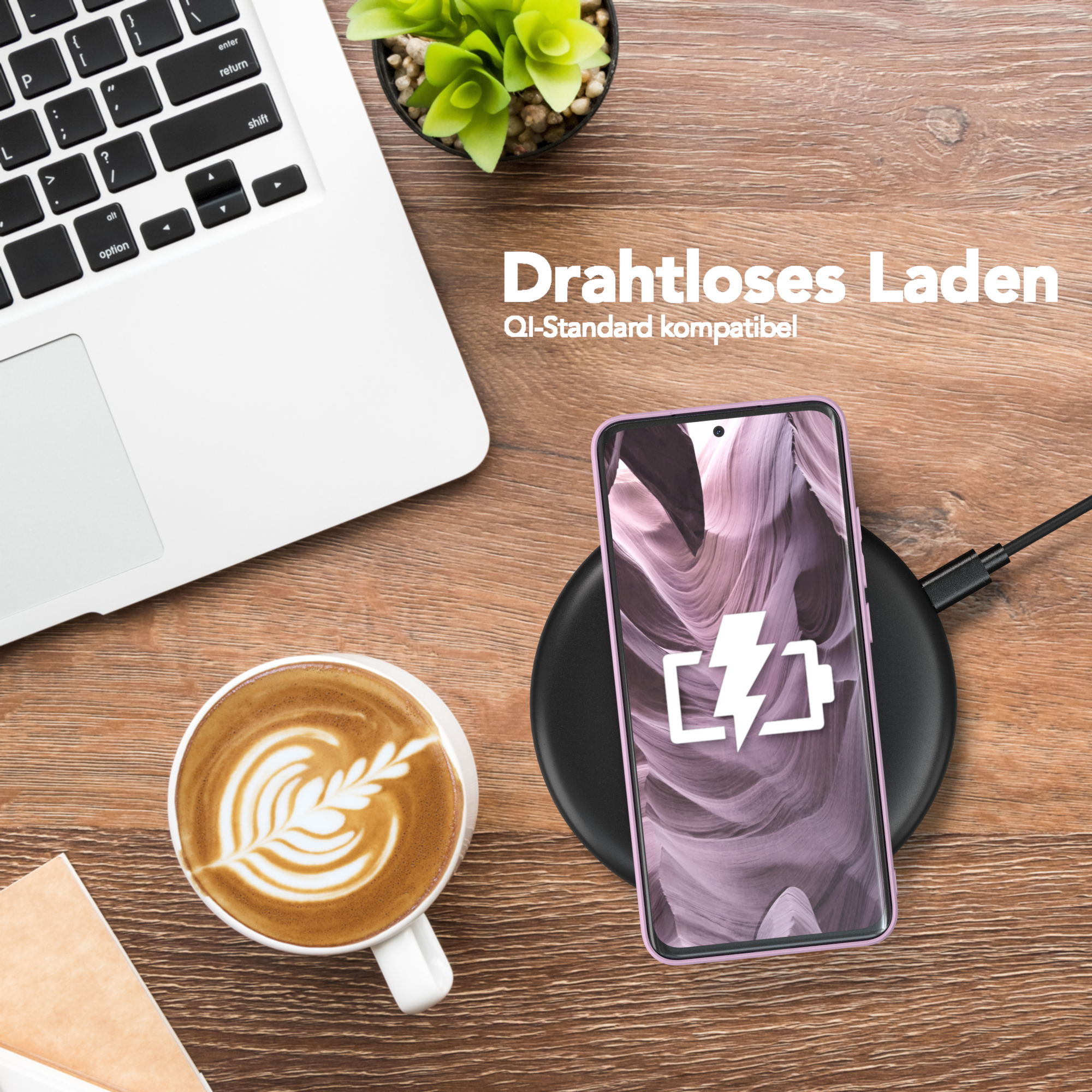 Ein Telefon mit lila Hülle liegt auf einem kabellosen Ladegerät. Ein Laptop, Kaffee und eine kleine Pflanze befinden sich ebenfalls auf dem Schreibtisch.