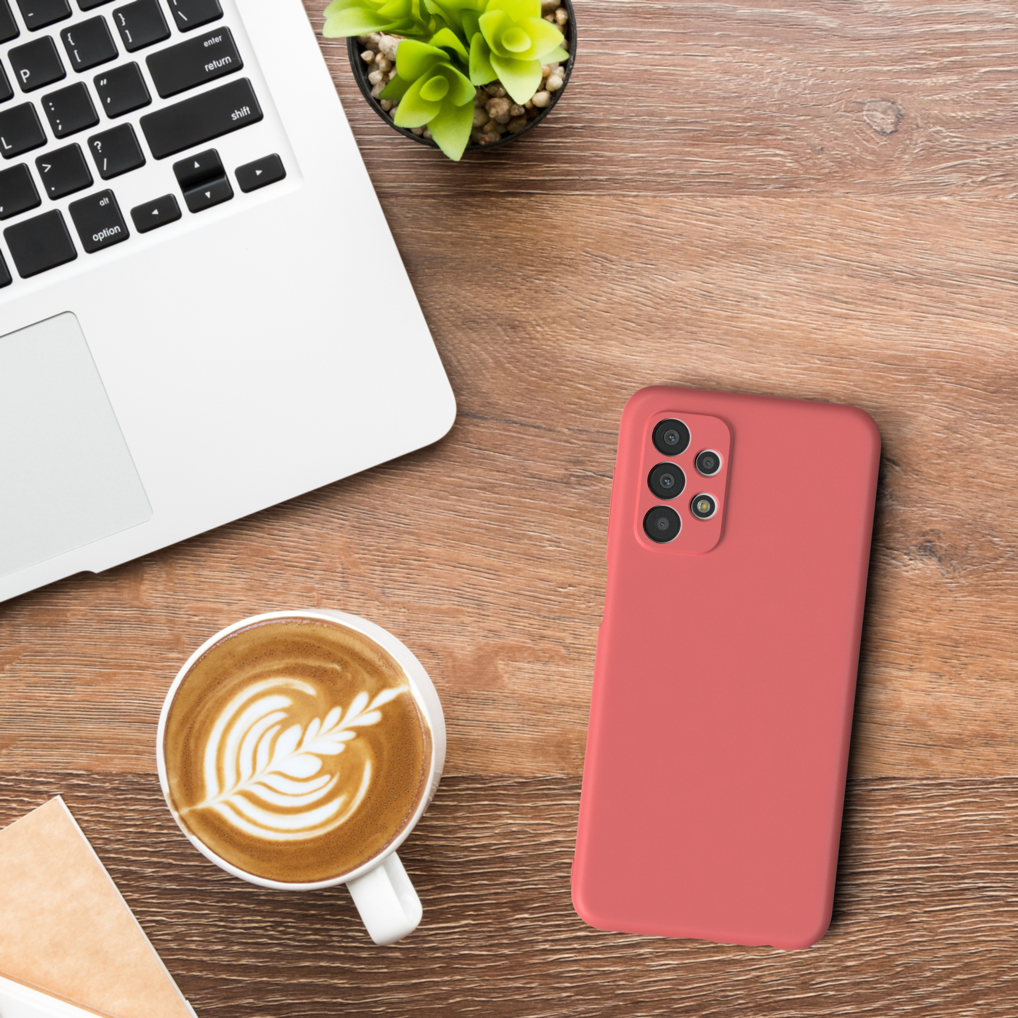 Eine rote Handyhülle liegt auf einem Holzschreibtisch neben einer Kaffeetasse und einem Laptop.