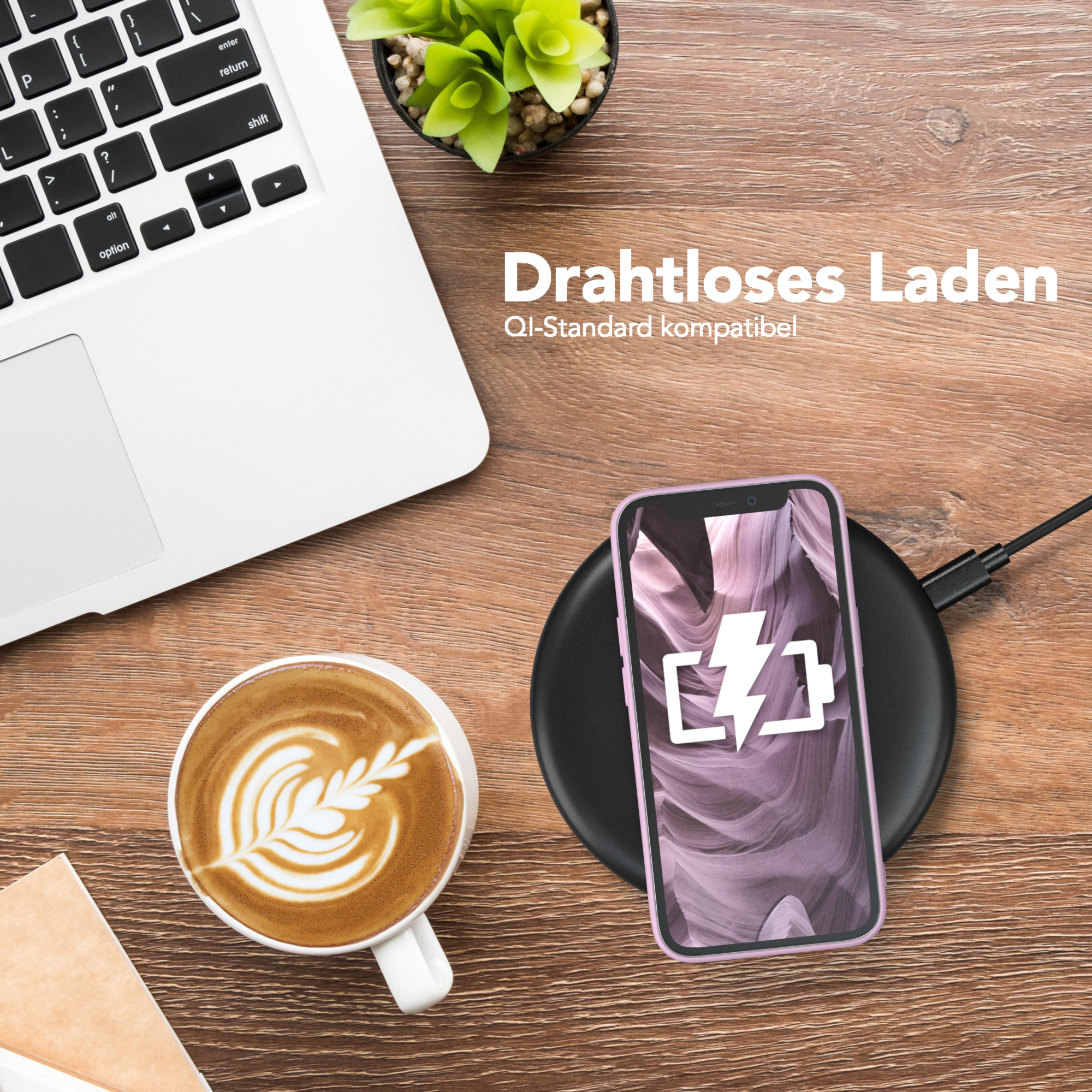 Ein Telefon in einer Hülle auf einem Ladepad. Laptop, Kaffee und eine Pflanze sind ebenfalls sichtbar.