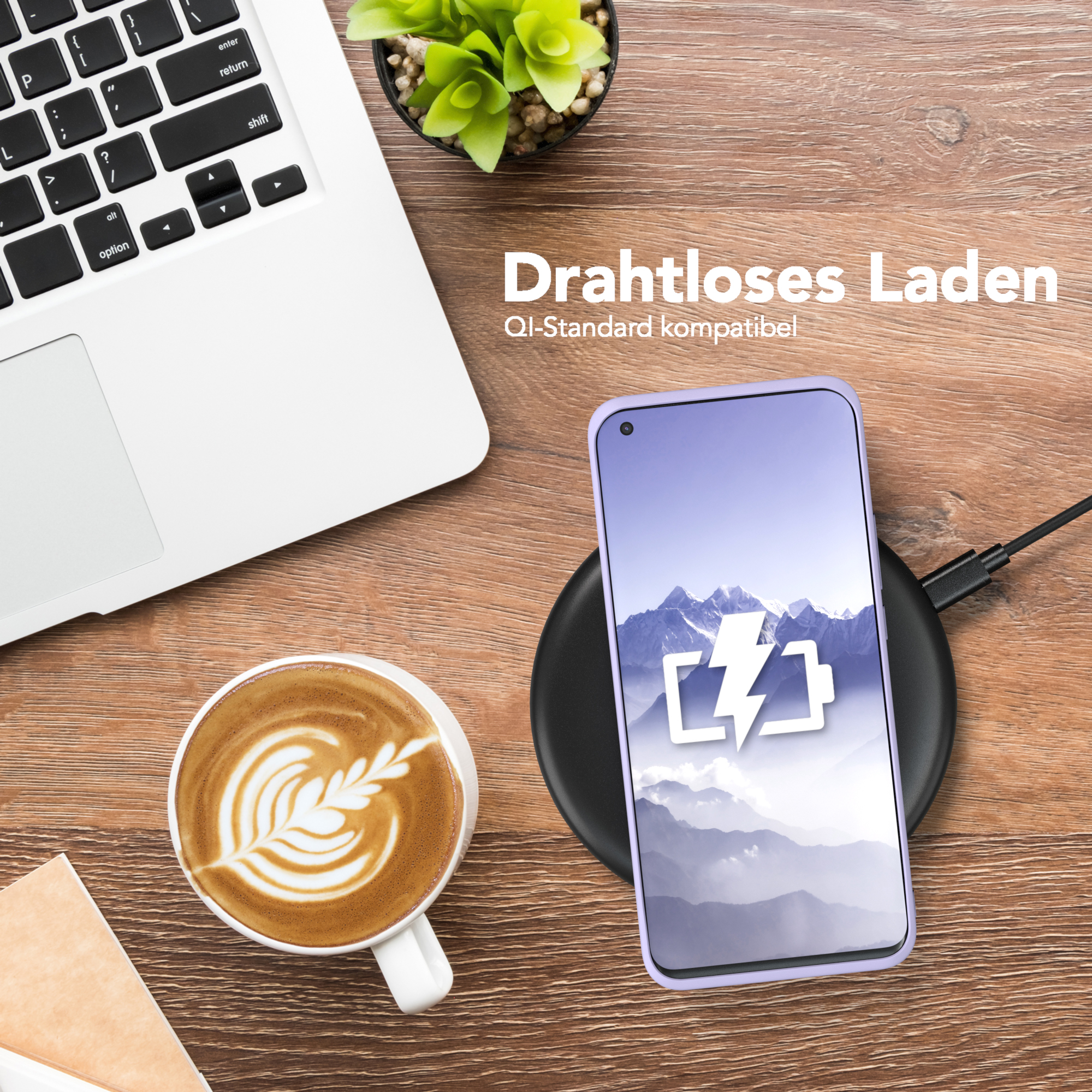 Telefon mit Hülle wird kabellos geladen. Laptop, Kaffee und Pflanze stehen auf dem Holztisch.