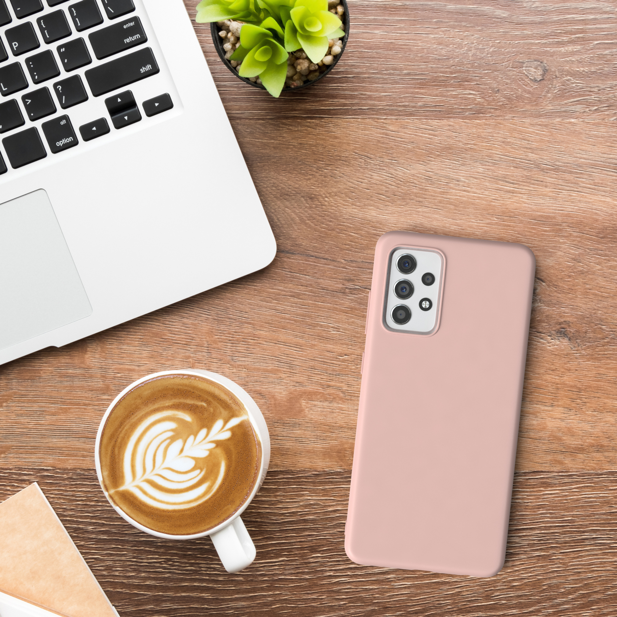 Eine Handyhülle, ein Laptop, eine Tasse Kaffee und eine Pflanze auf einem Holztisch.
