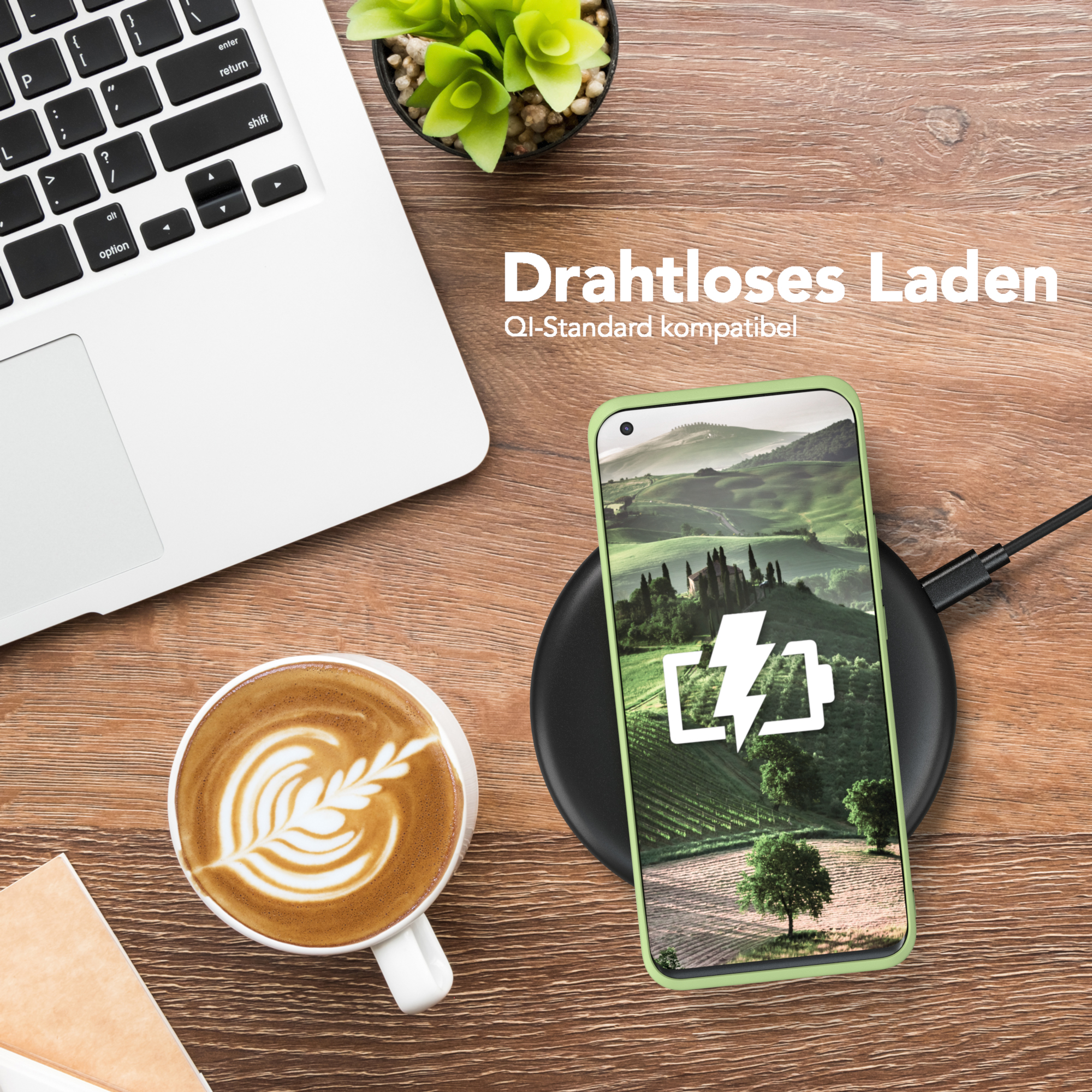 Ein Telefon mit grüner Hülle liegt auf einem Ladepad. Daneben stehen ein Laptop und eine Kaffeetasse.