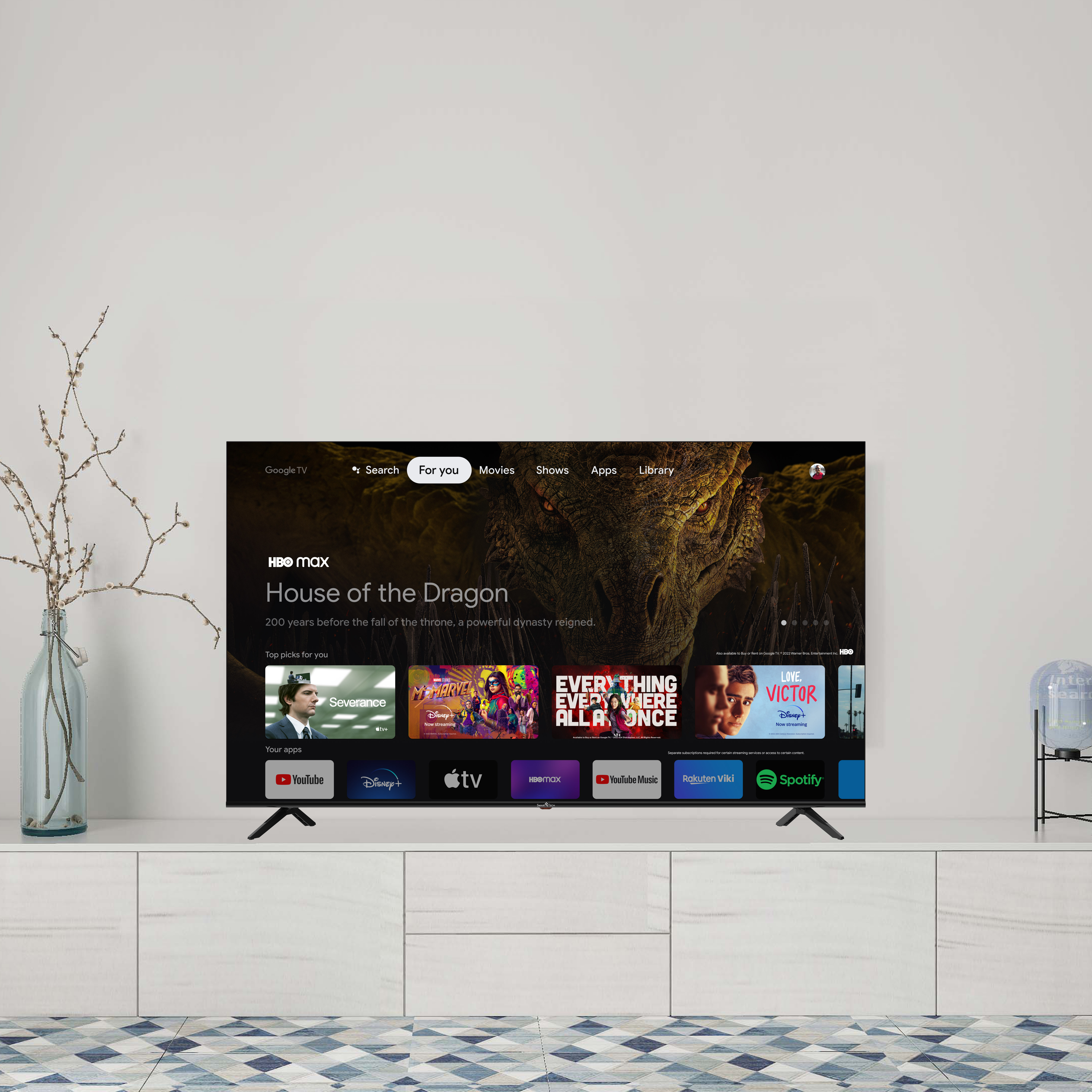 Un televisore moderno mostra l'app HBO Max e i contenuti contro un muro bianco. La TV è su un mobile.
