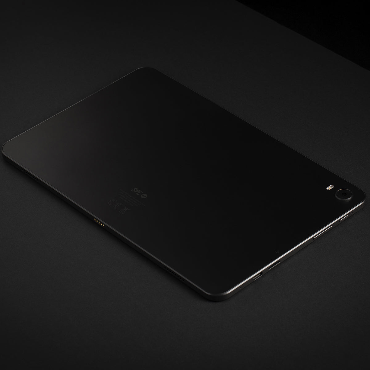 Tablet nero su una superficie nera. Il tablet ha una fotocamera sul retro.