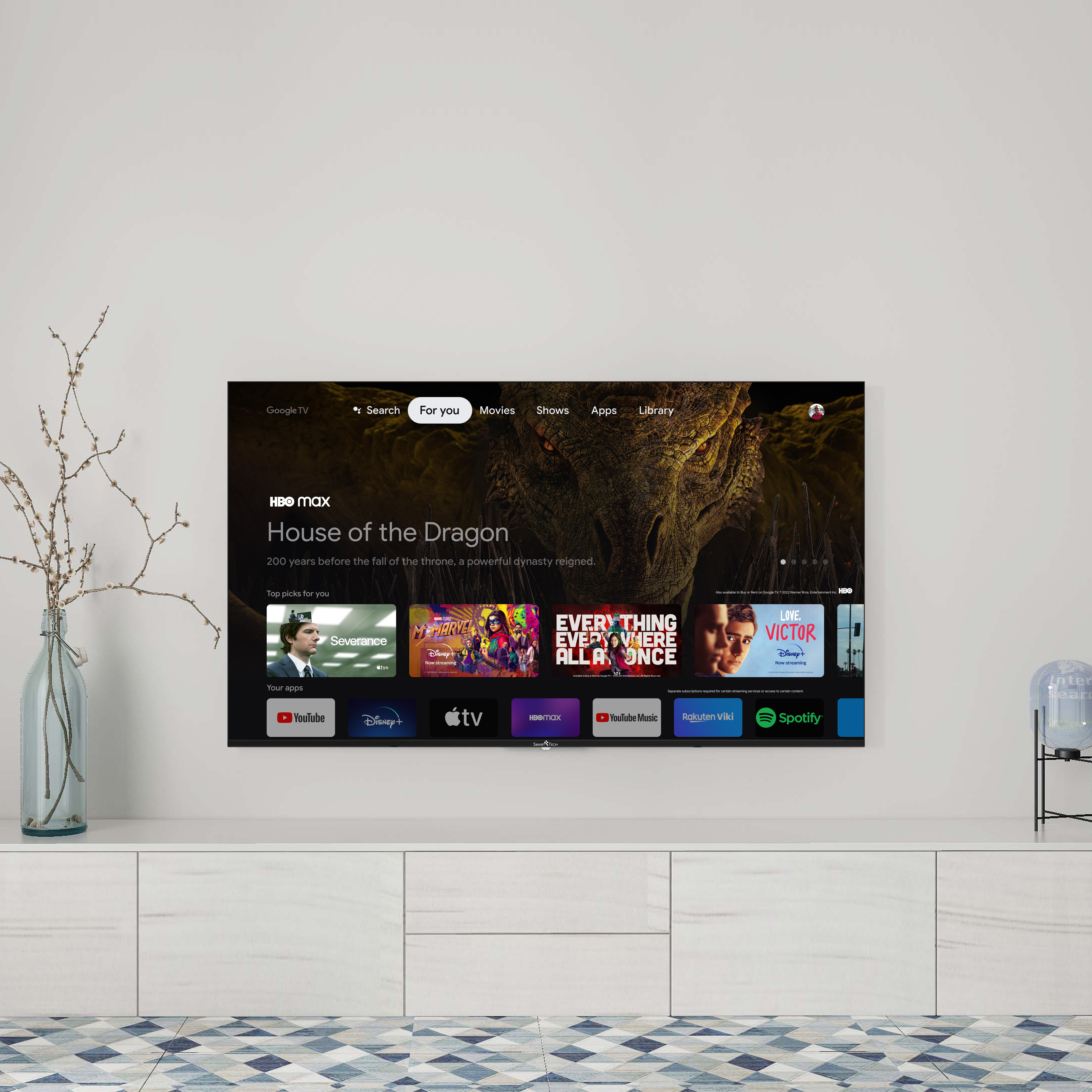 Telewizor pokazujący interfejs HBO Max z serialem House of the Dragon. Telewizor stoi na białej szafce.