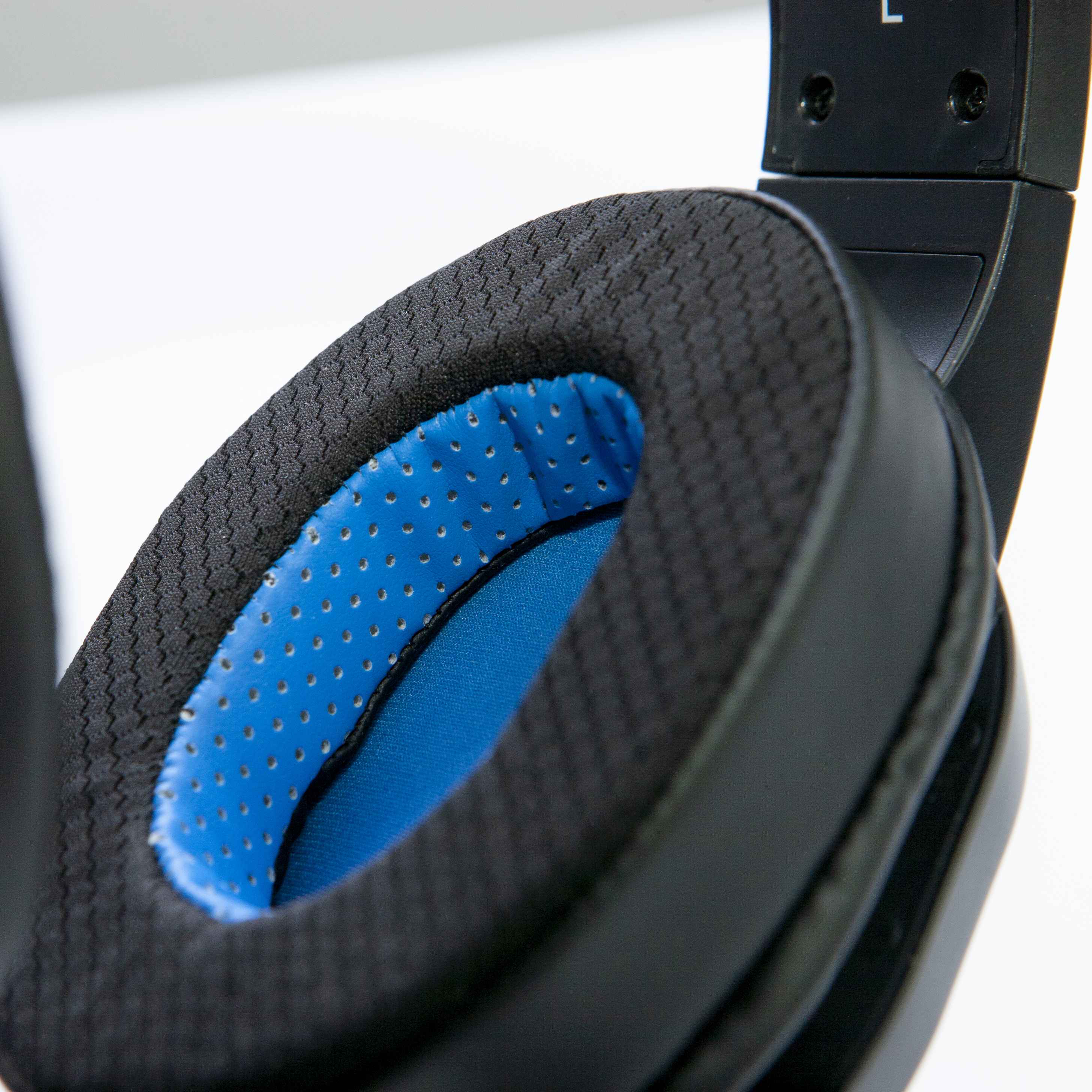 Primo piano di un padiglione auricolare nero con tessuto interno blu visibile.
