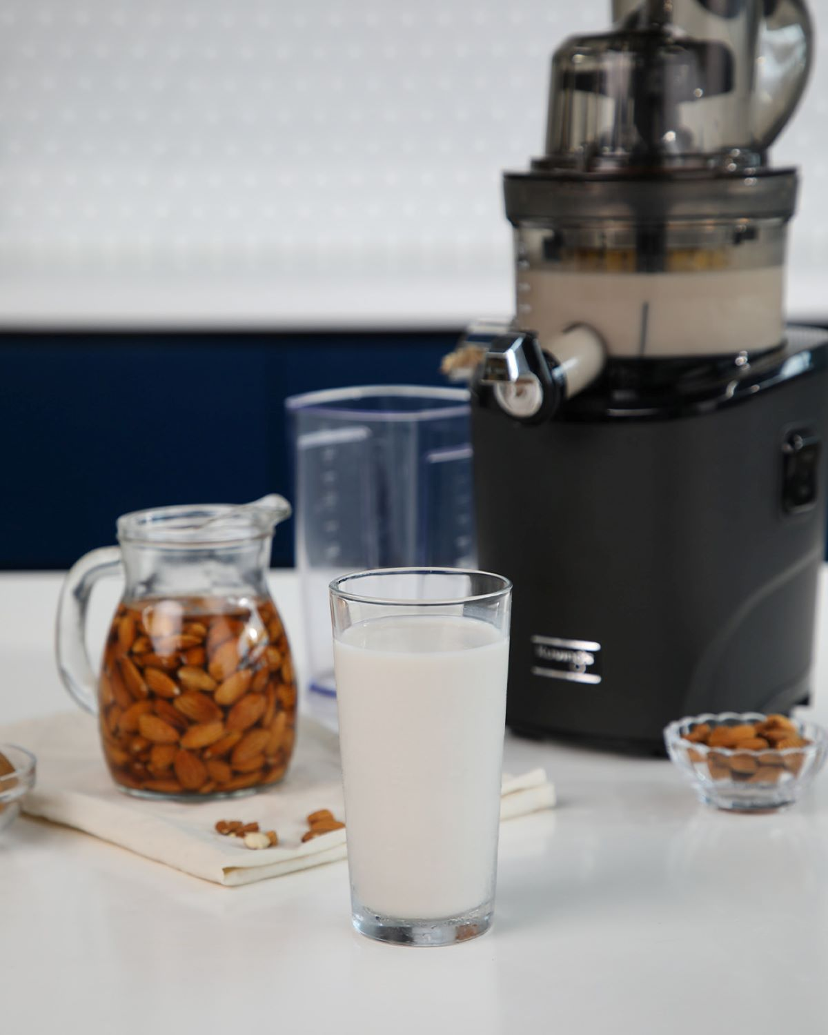 Hacedor de zumo con zumo e ingredientes. Leche de almendras en vaso. Almendras.