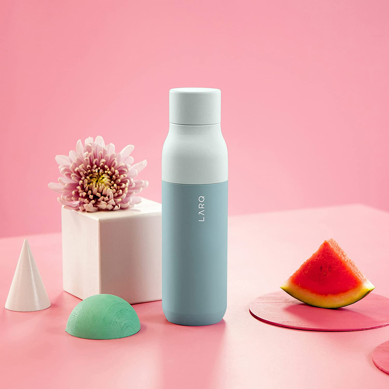 Eine blau-weiße Flasche mit Wassermelonenscheibe und dekorativen Objekten.