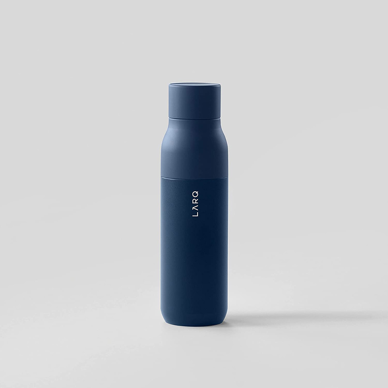 Eine marineblaue Wasserflasche mit weißem LARQ-Logo, vor schlichtem, hellgrauem Hintergrund.
