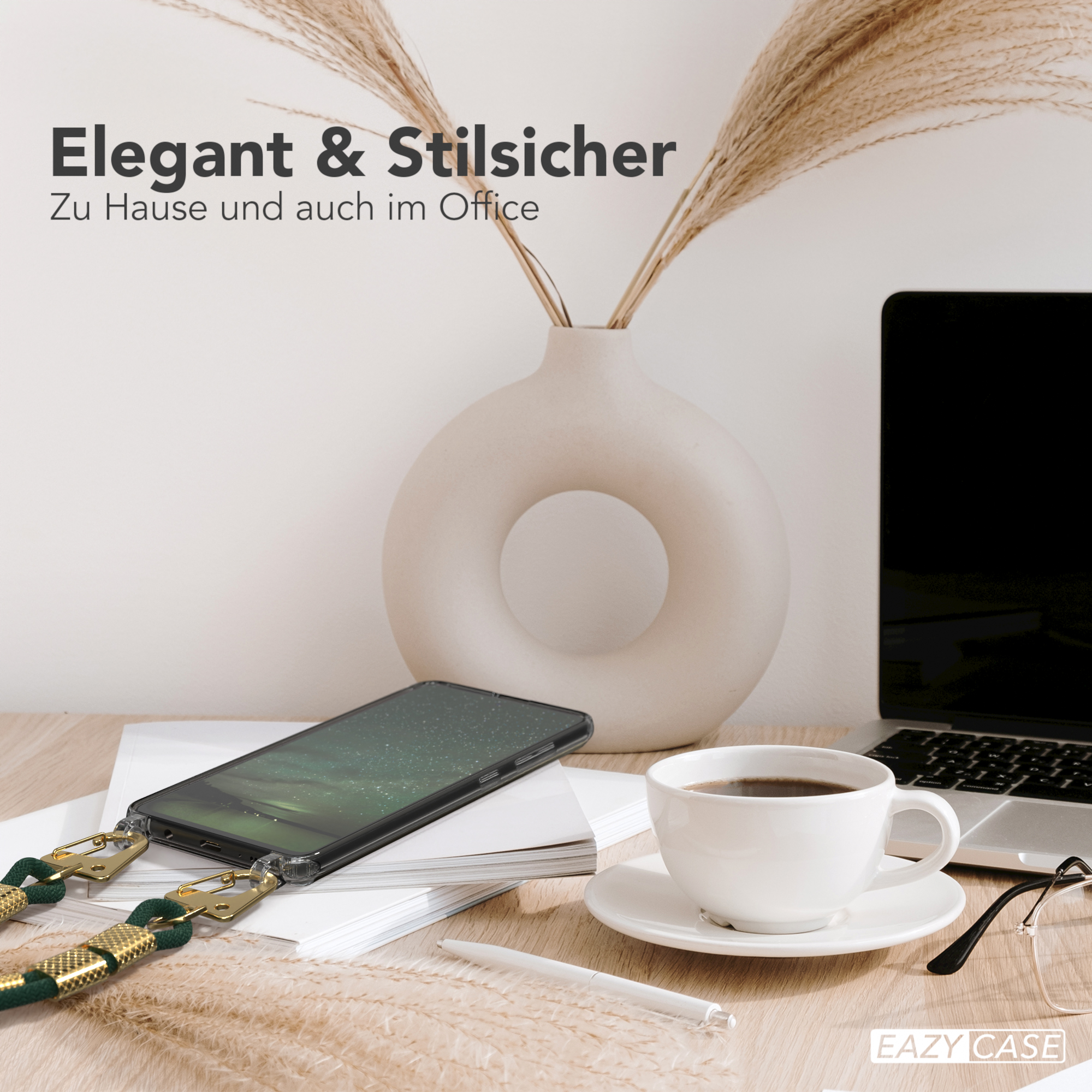 Ein Telefon mit Hülle und Riemen, eine Kaffeetasse und Schreibtischutensilien auf einem Holzschreibtisch, neutrale Töne.