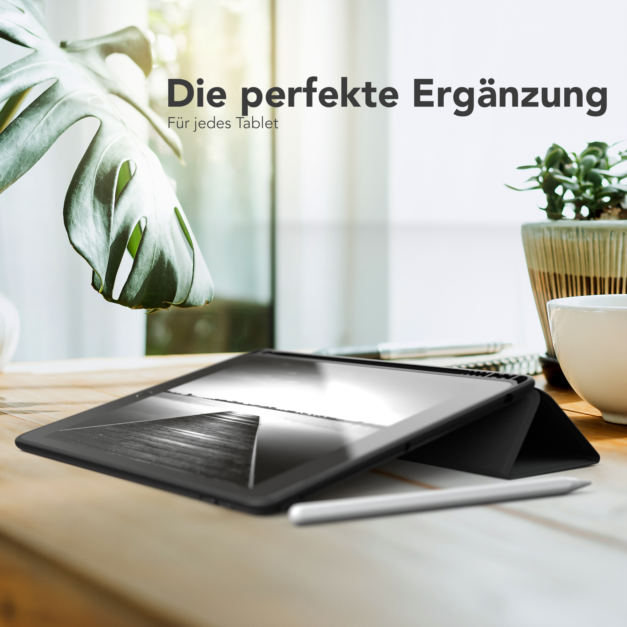 Tablet in einer schwarzen Hülle auf einem Holztisch mit Pflanze und Stift. Text sagt "Die perfekte Ergänzung".