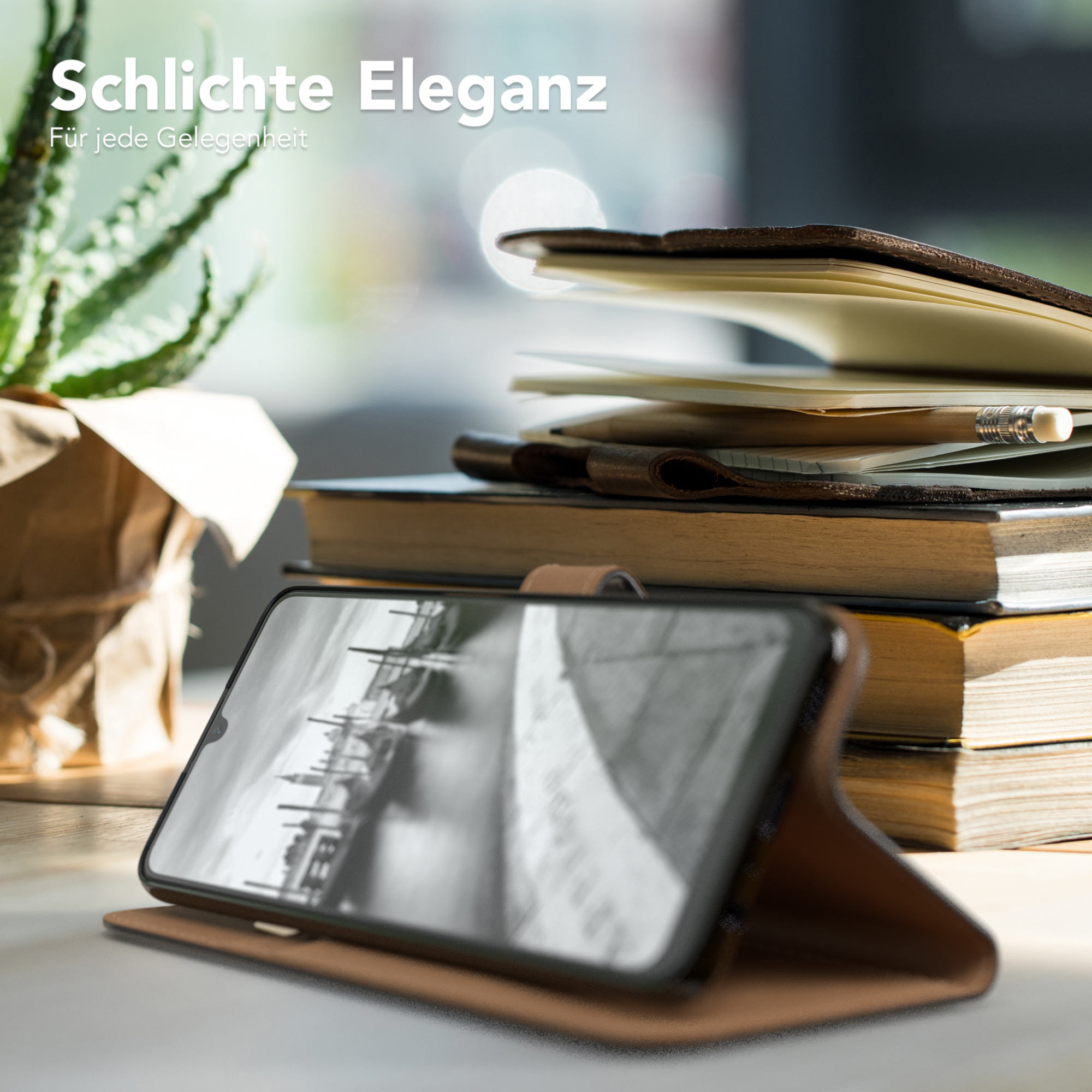 Ein Telefon liegt in einer Hülle auf einem Tisch, im Hintergrund Bücher und eine Pflanze.