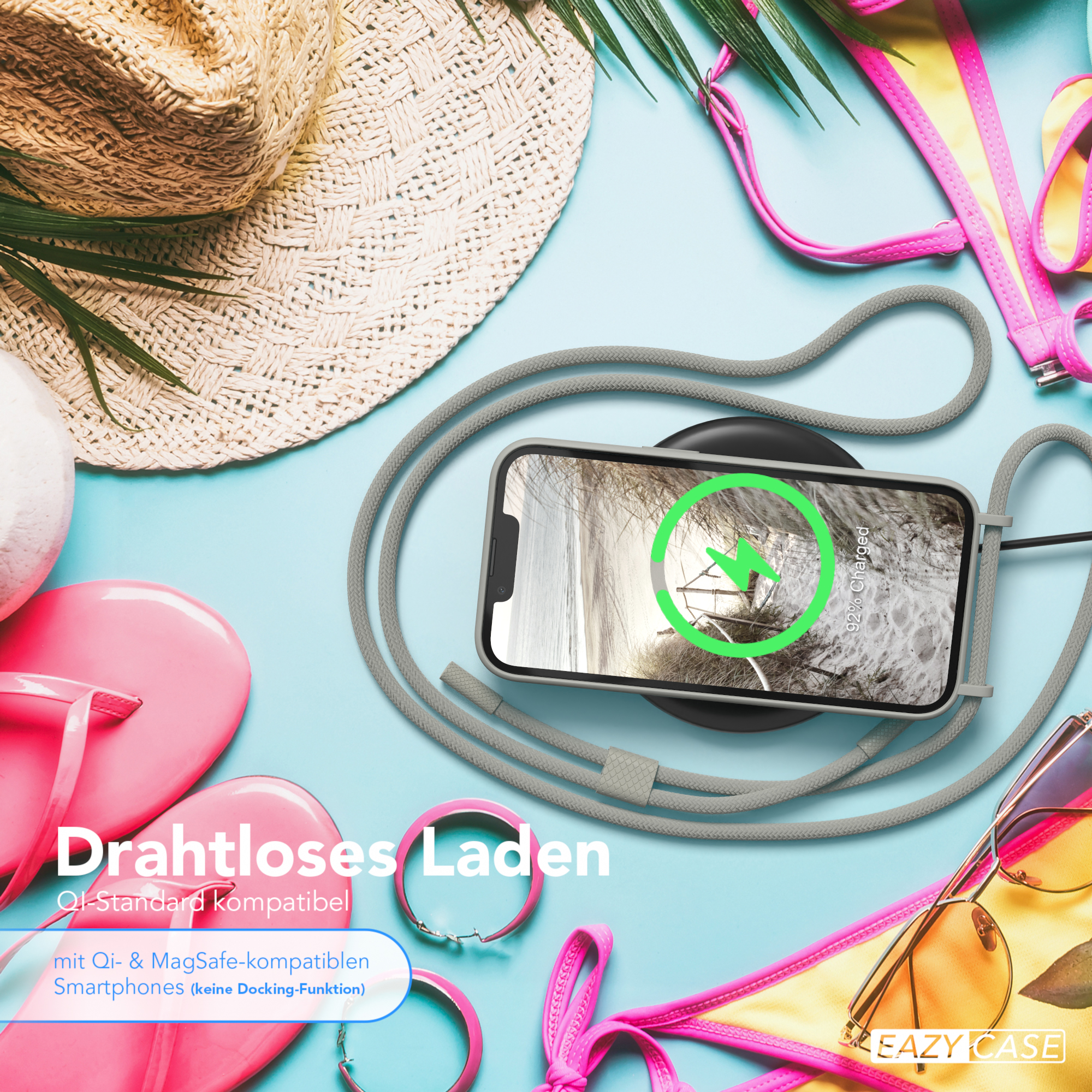 Telefon auf einem kabellosen Ladegerät, plus Strandartikel.