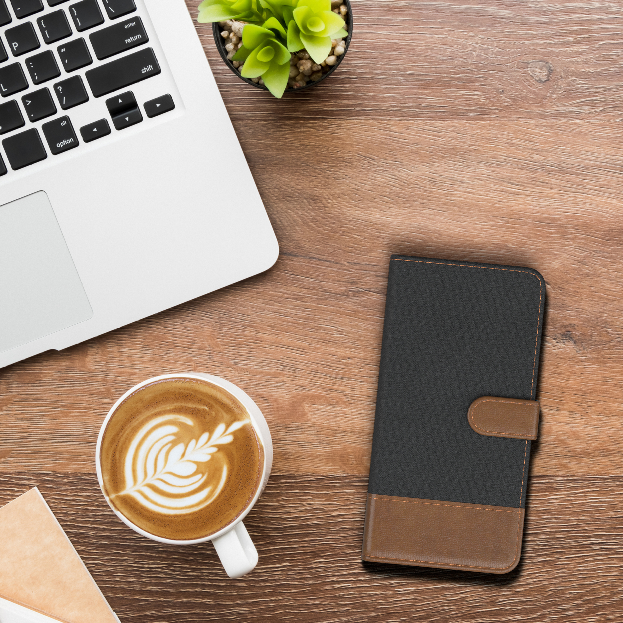 Laptop, Kaffeetasse und Handyhülle auf Holztisch. Hülle ist schwarz-braun.