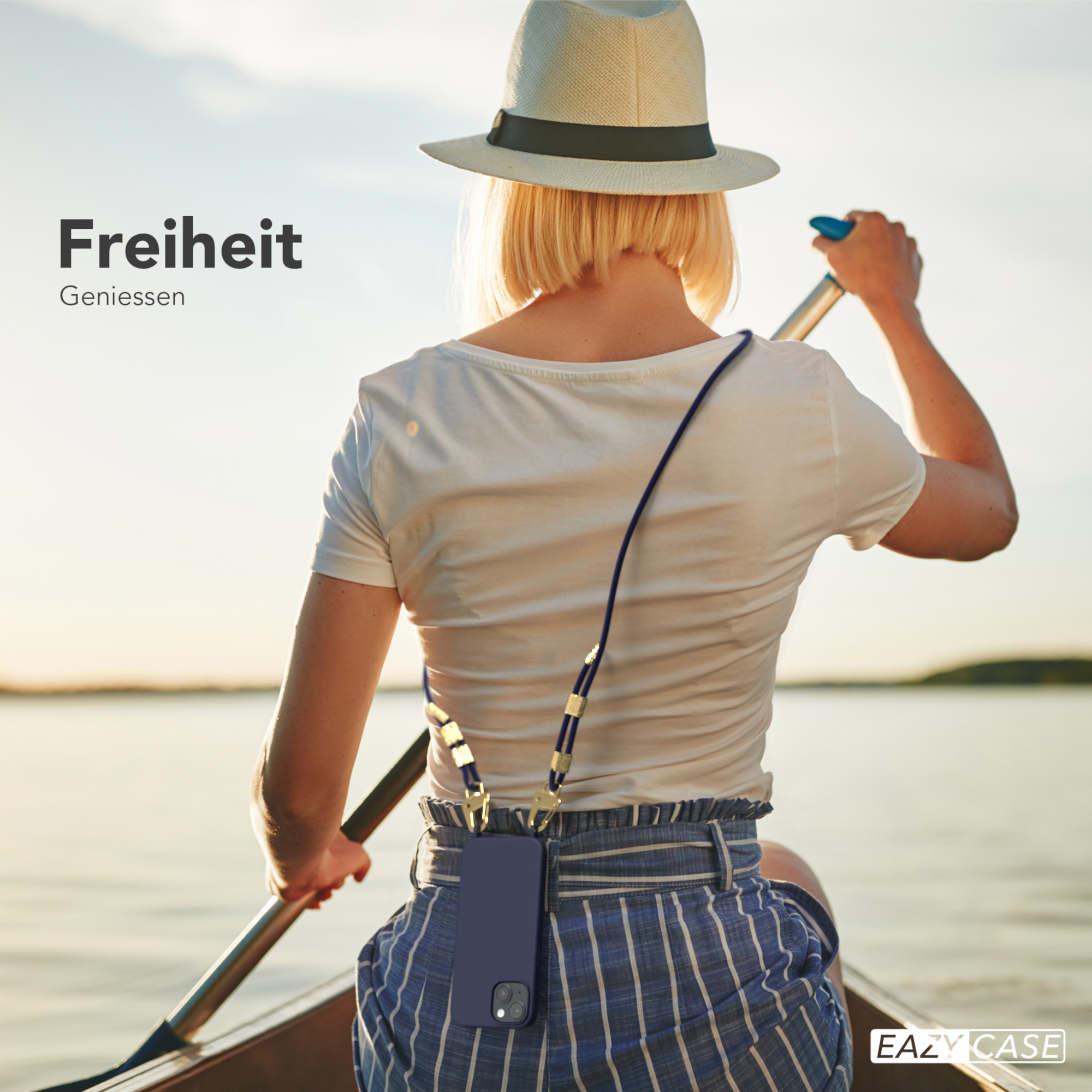 Eine Frau in einem Boot, paddelnd, mit einem Telefon an einem Lanyard, mit Wasser und Sonnenuntergang im Hintergrund.