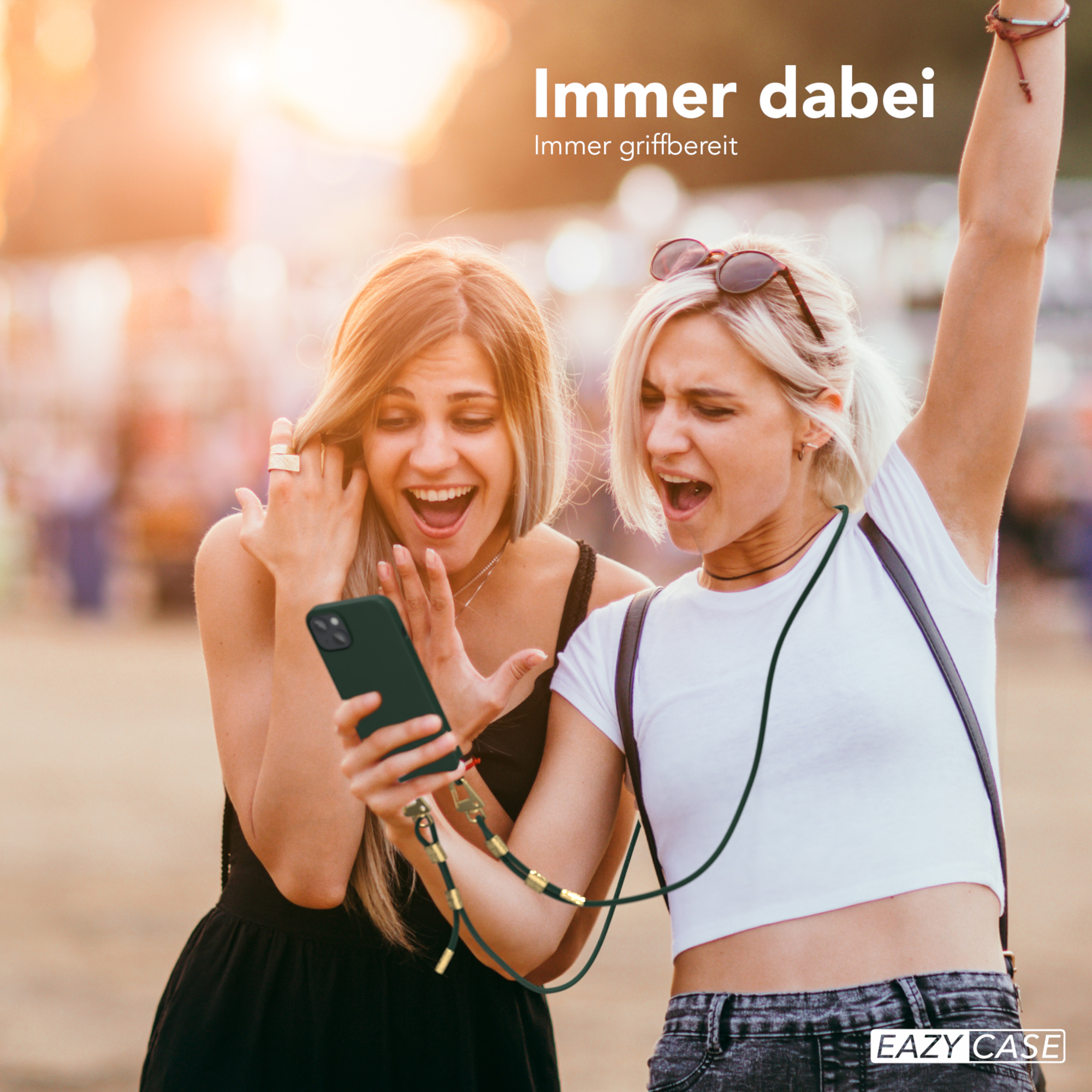 Zwei Frauen im Freien, schauen auf ein Telefon mit einem Lanyard. Der Himmel ist unscharf.