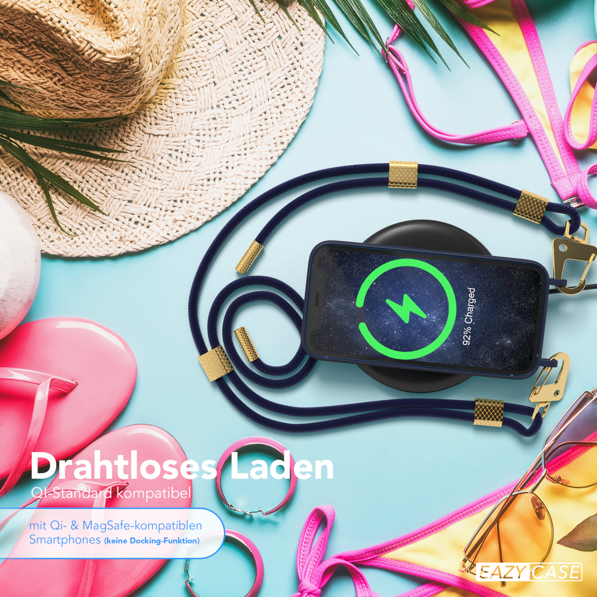 Telefon lädt auf schwarzem Pad, umgeben von Strandutensilien: Hut, Flip-Flops und Bikini.
