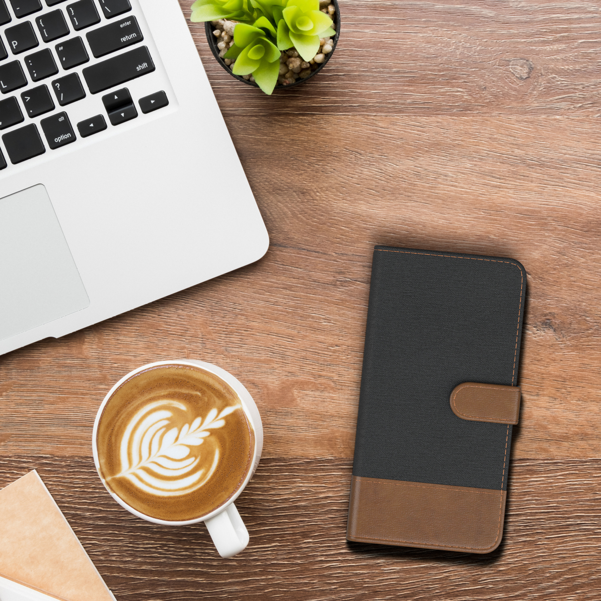 Büroszene. Laptop, Kaffeetasse und eine Handyhülle auf dem Schreibtisch. Die Szene ist gut beleuchtet.