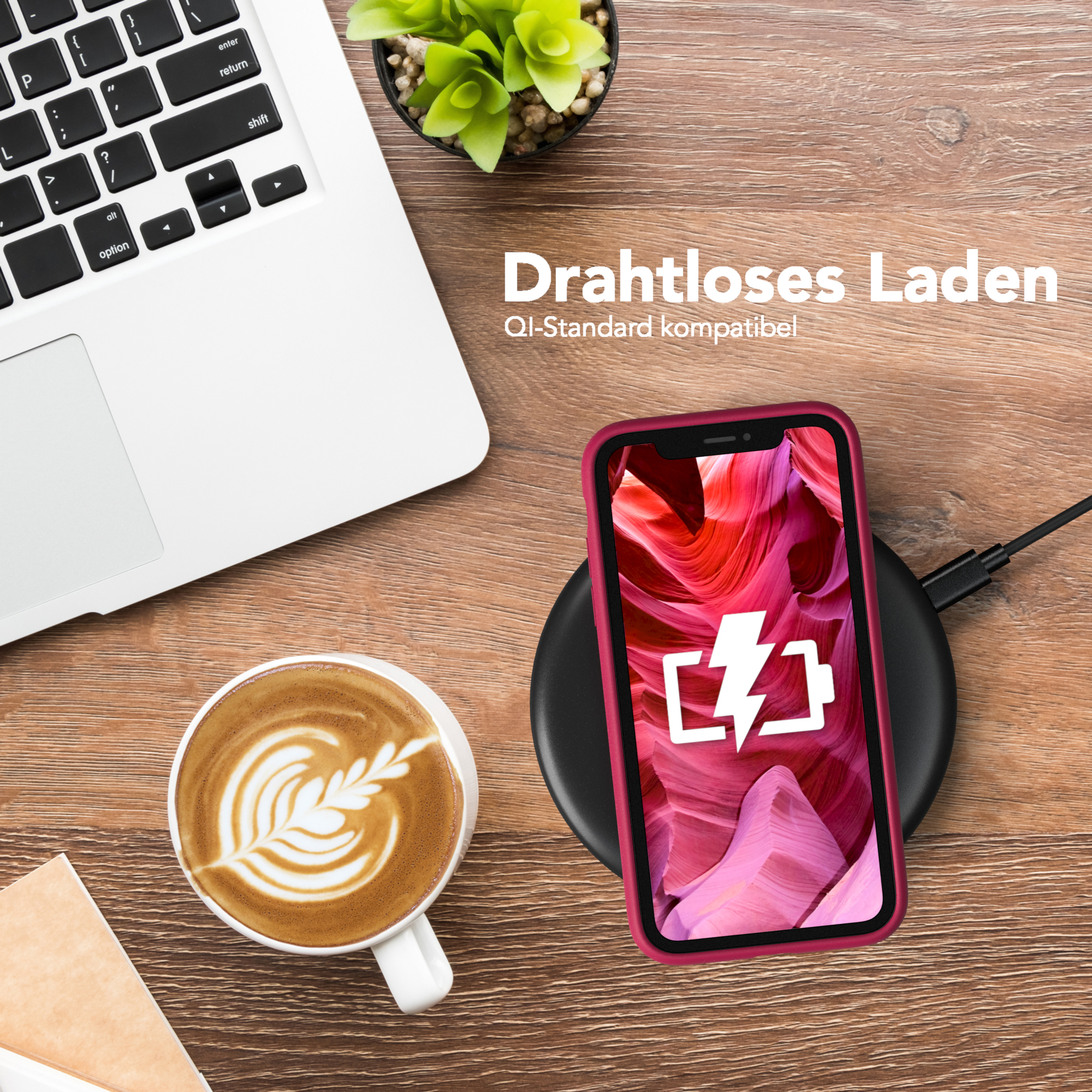 Telefon wird drahtlos auf einem Pad geladen. Kaffeetasse und Laptop auf dem Tisch.