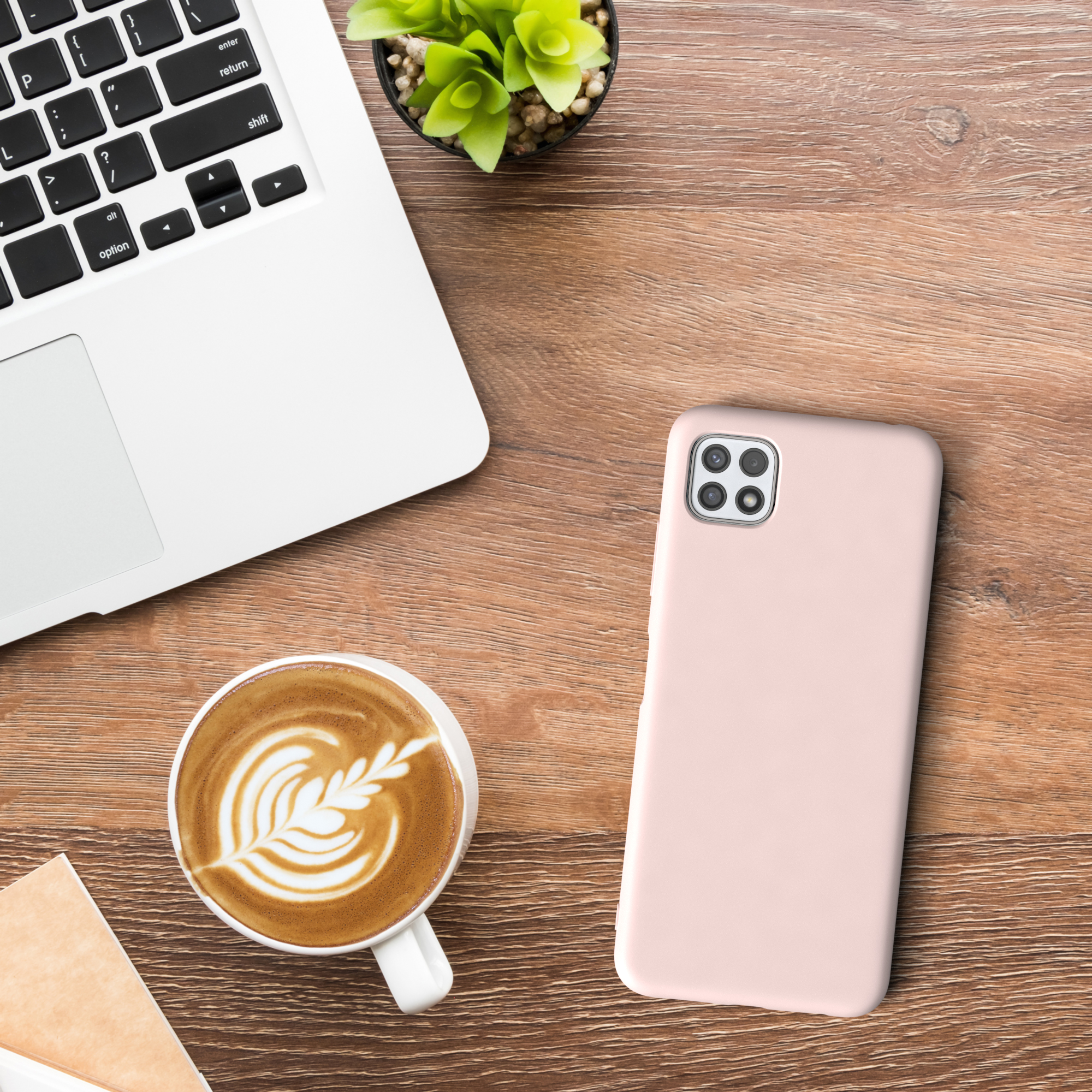 Ein Telefon und eine Kaffeetasse mit Latte Art. Kleine Pflanze und Laptop auf dem Holztisch.