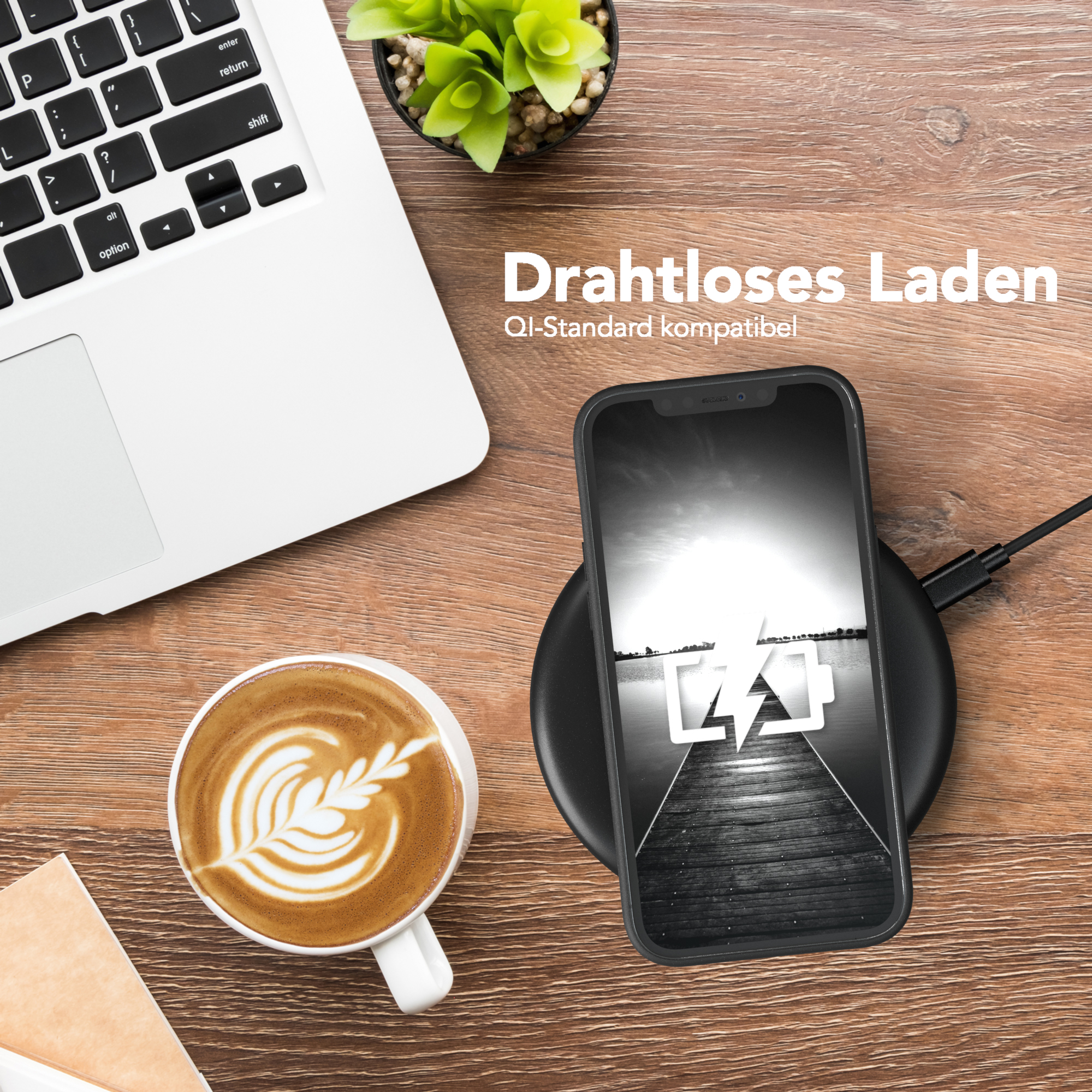 Telefon lädt kabellos neben Laptop und Kaffee.