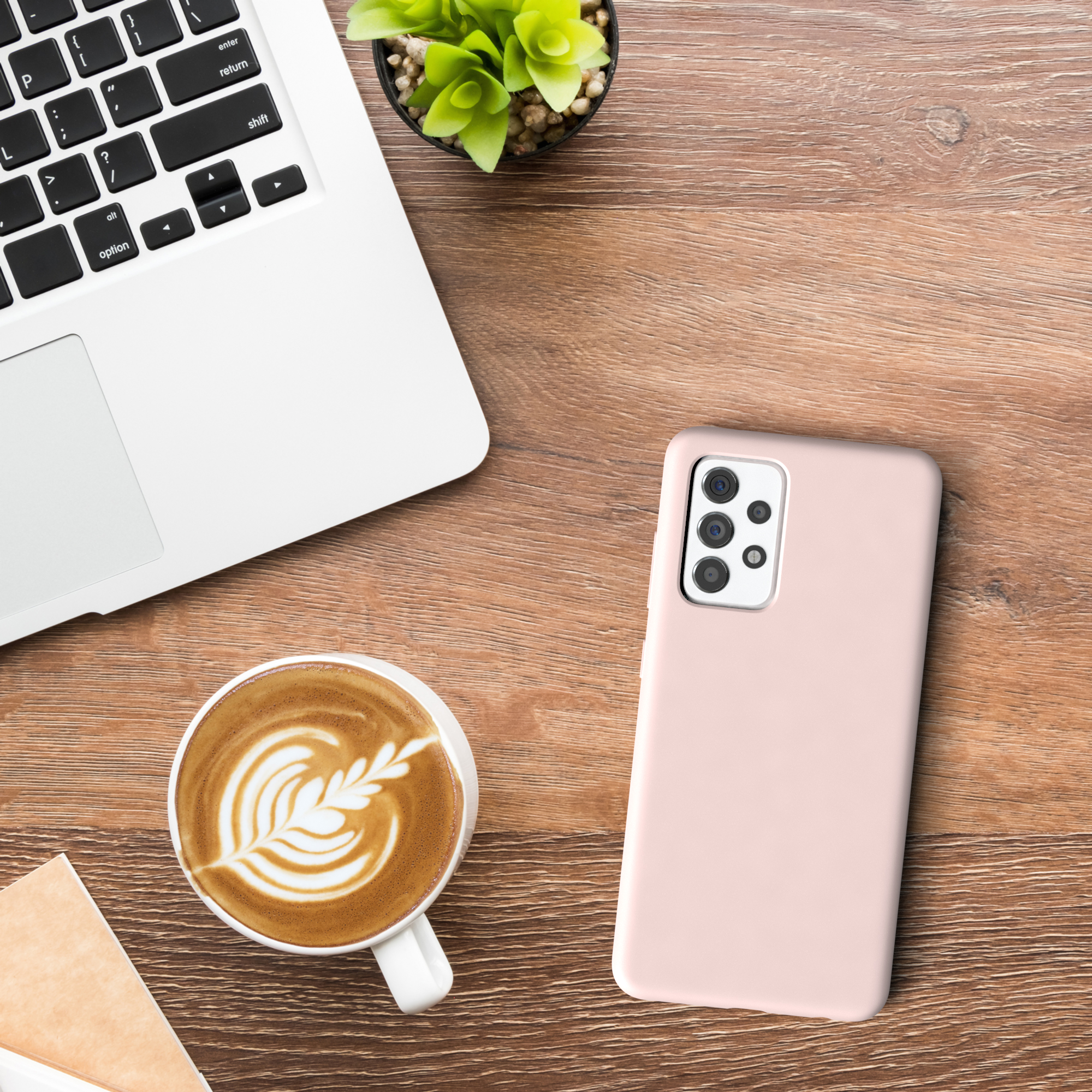 Laptop, Kaffee und eine pinke Handyhülle auf Holztisch. Draufsicht.