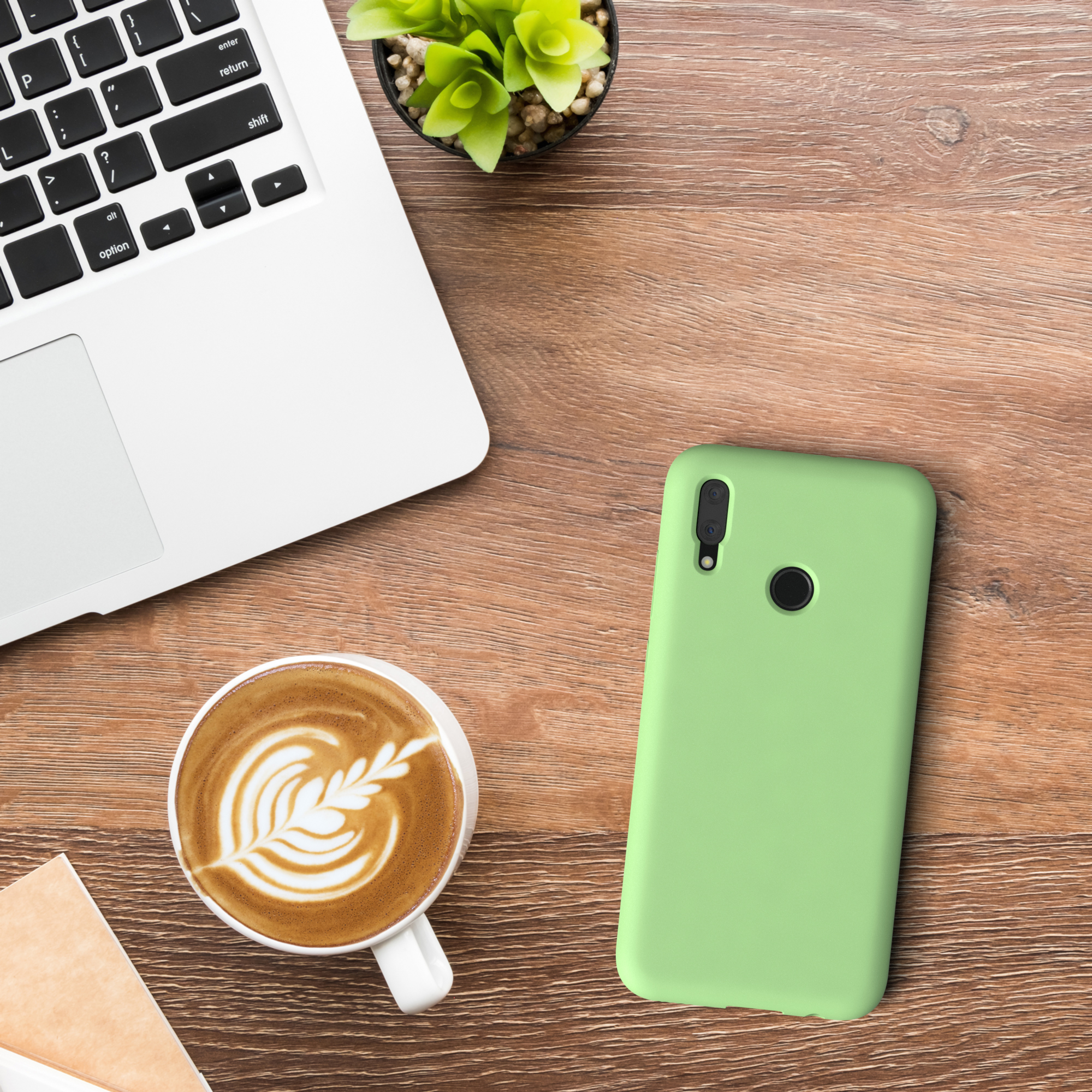 Laptop, mintgrüne Handyhülle und Kaffee mit Latte Art liegen auf einem Holztisch.