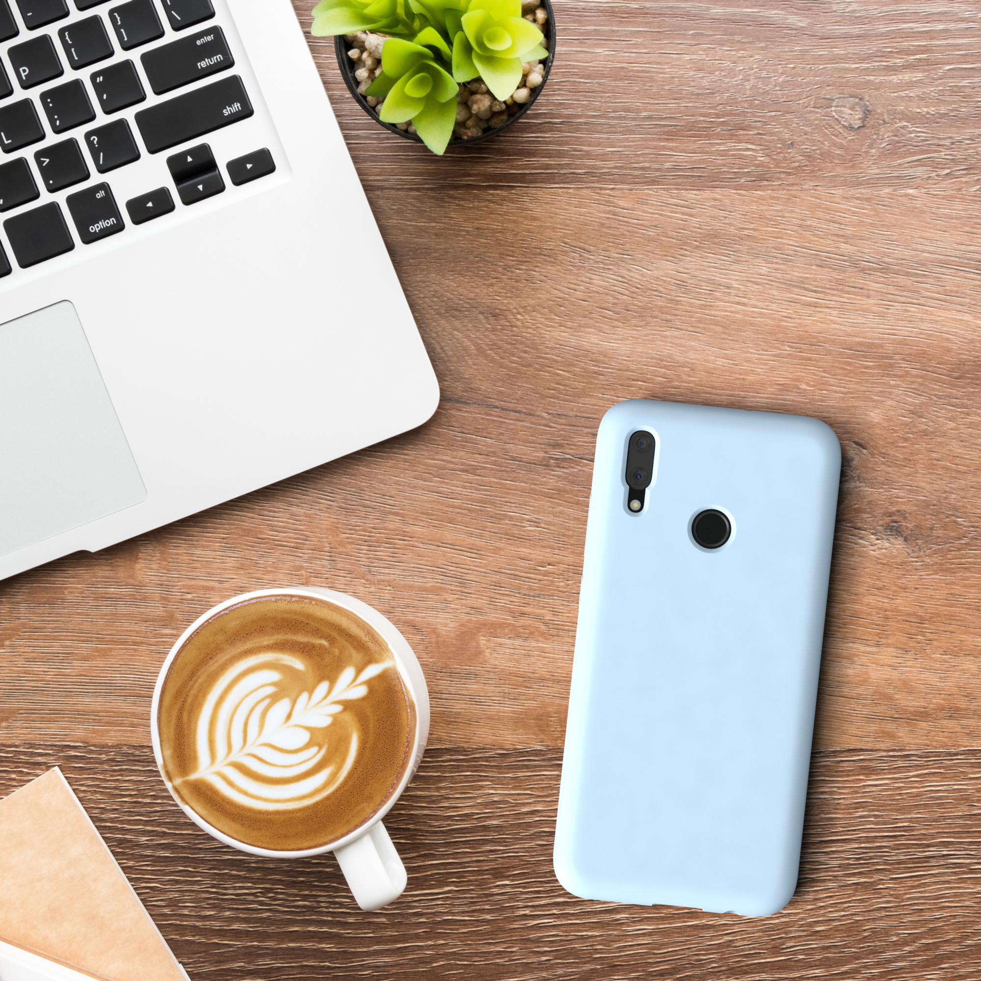 Ein Schreibtisch mit Laptop, Kaffeetasse, Telefon mit blauer Hülle und Pflanze.