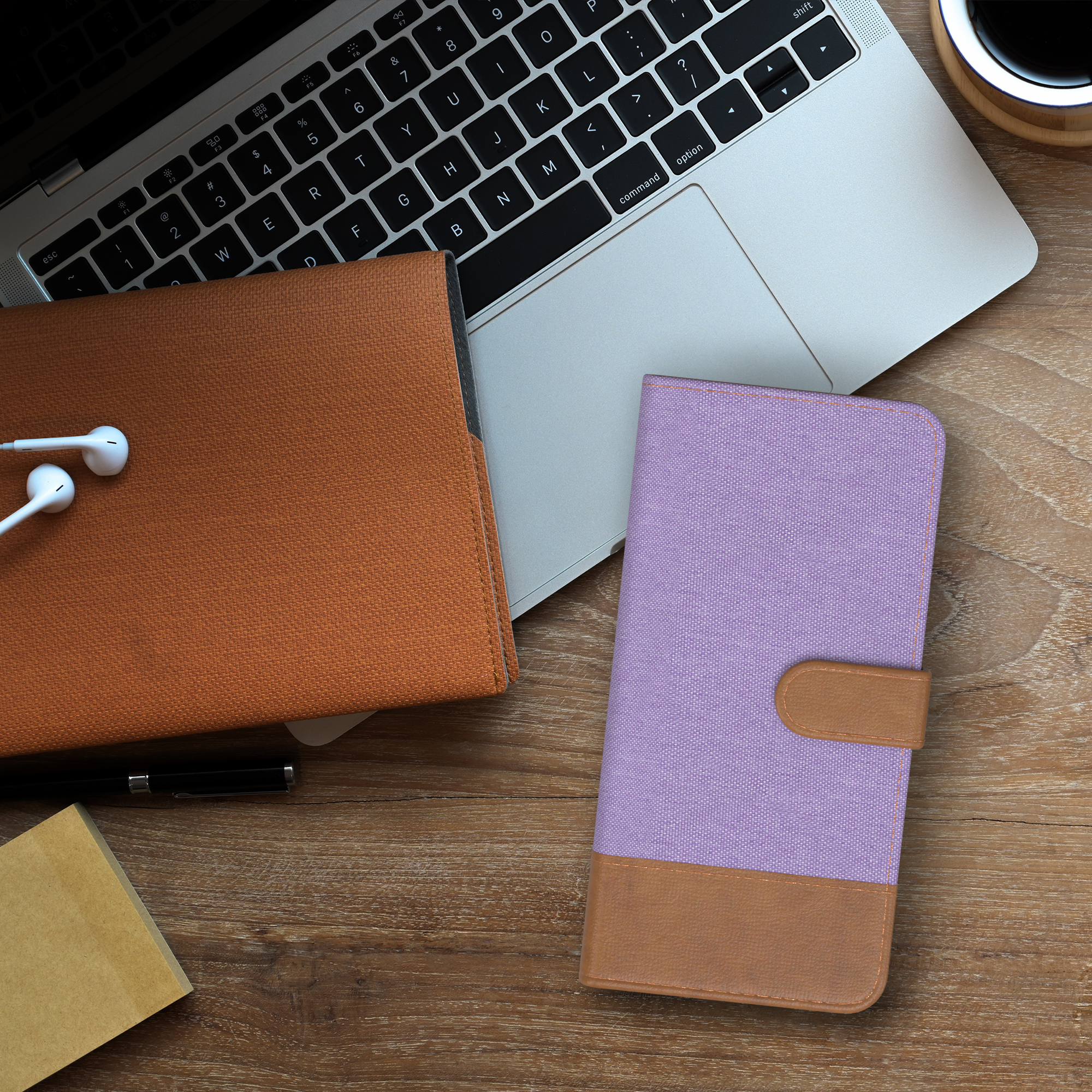 Draufsicht: Laptop, Ohrhörer und Handyhülle auf einem Holztisch.