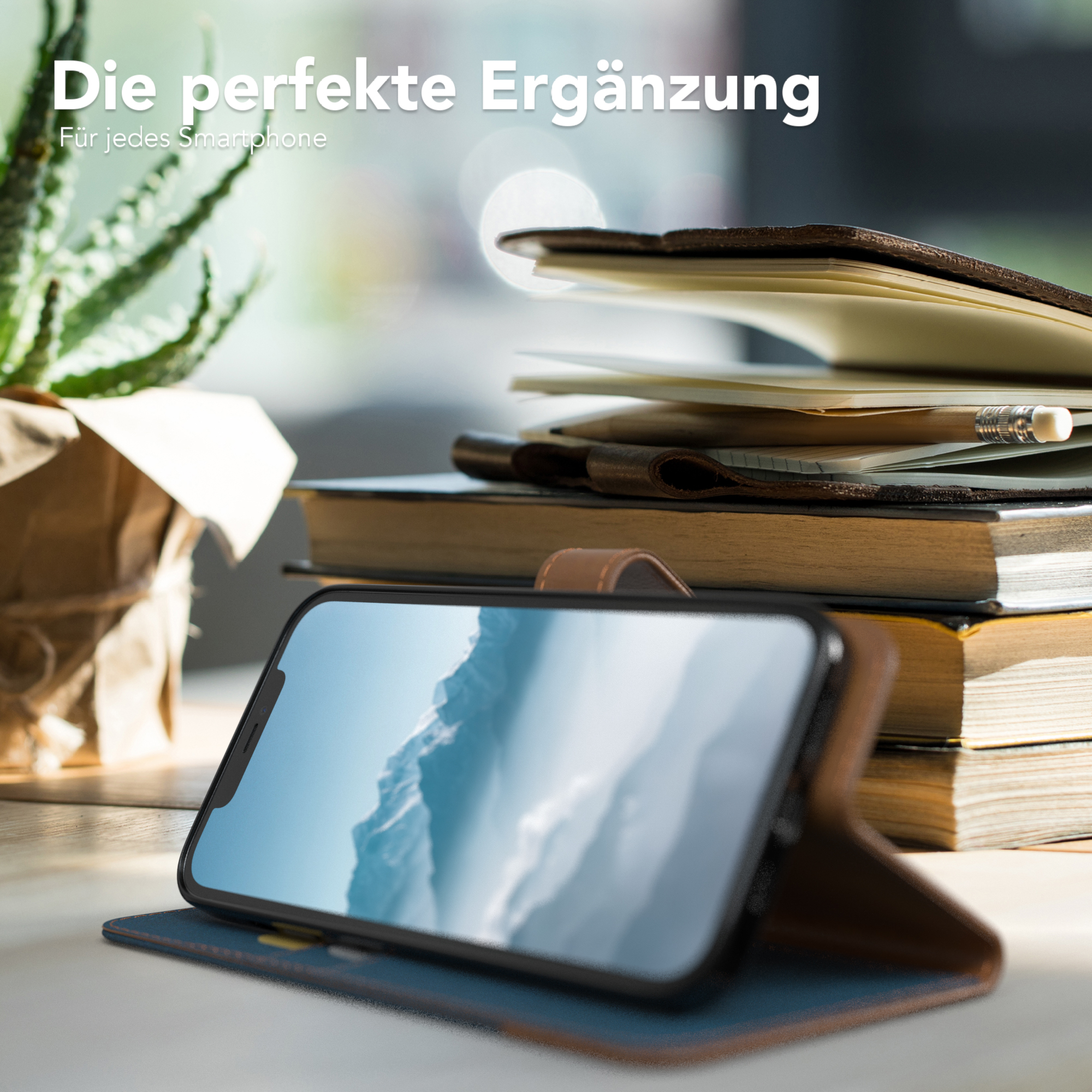 Telefon in brauner Hülle auf einem Holzschreibtisch, mit Büchern und einer Pflanze.