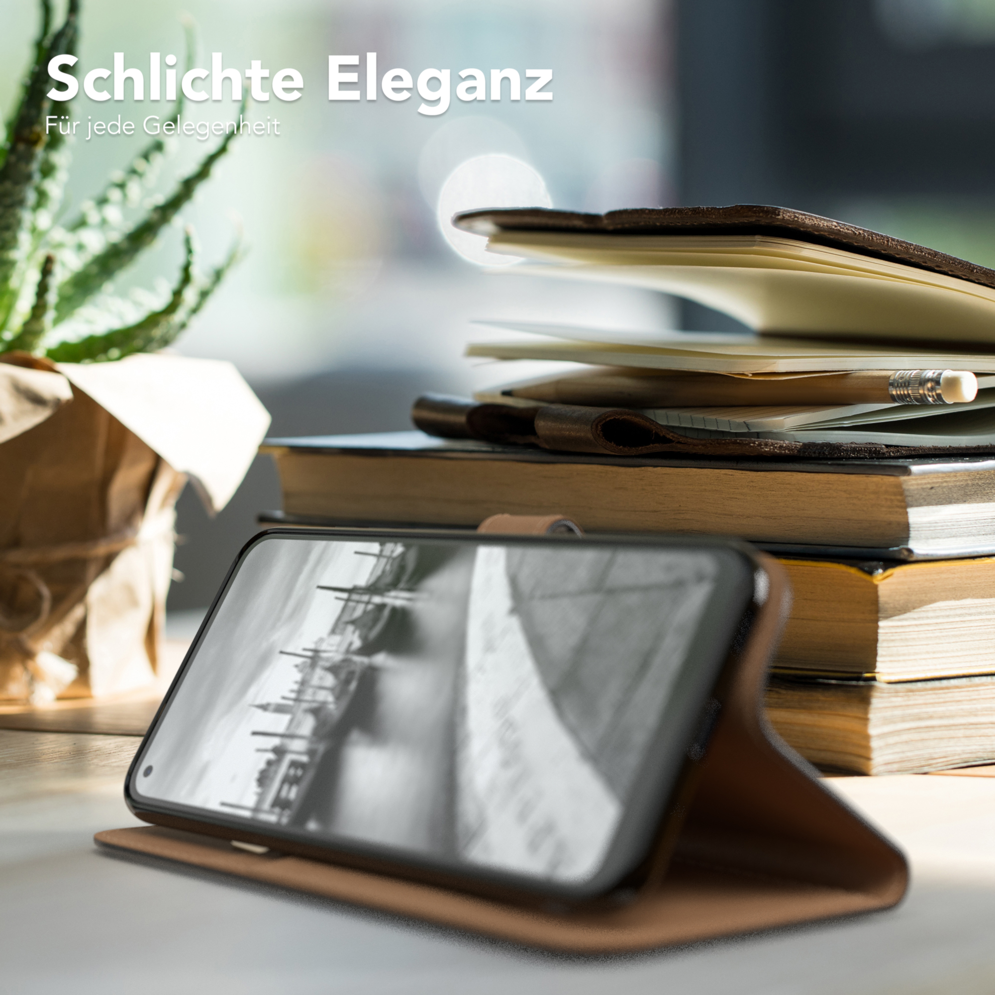 Telefon in brauner Leder-Geldbörsenhülle auf Tisch mit Büchern. Text: Schlichte Eleganz.