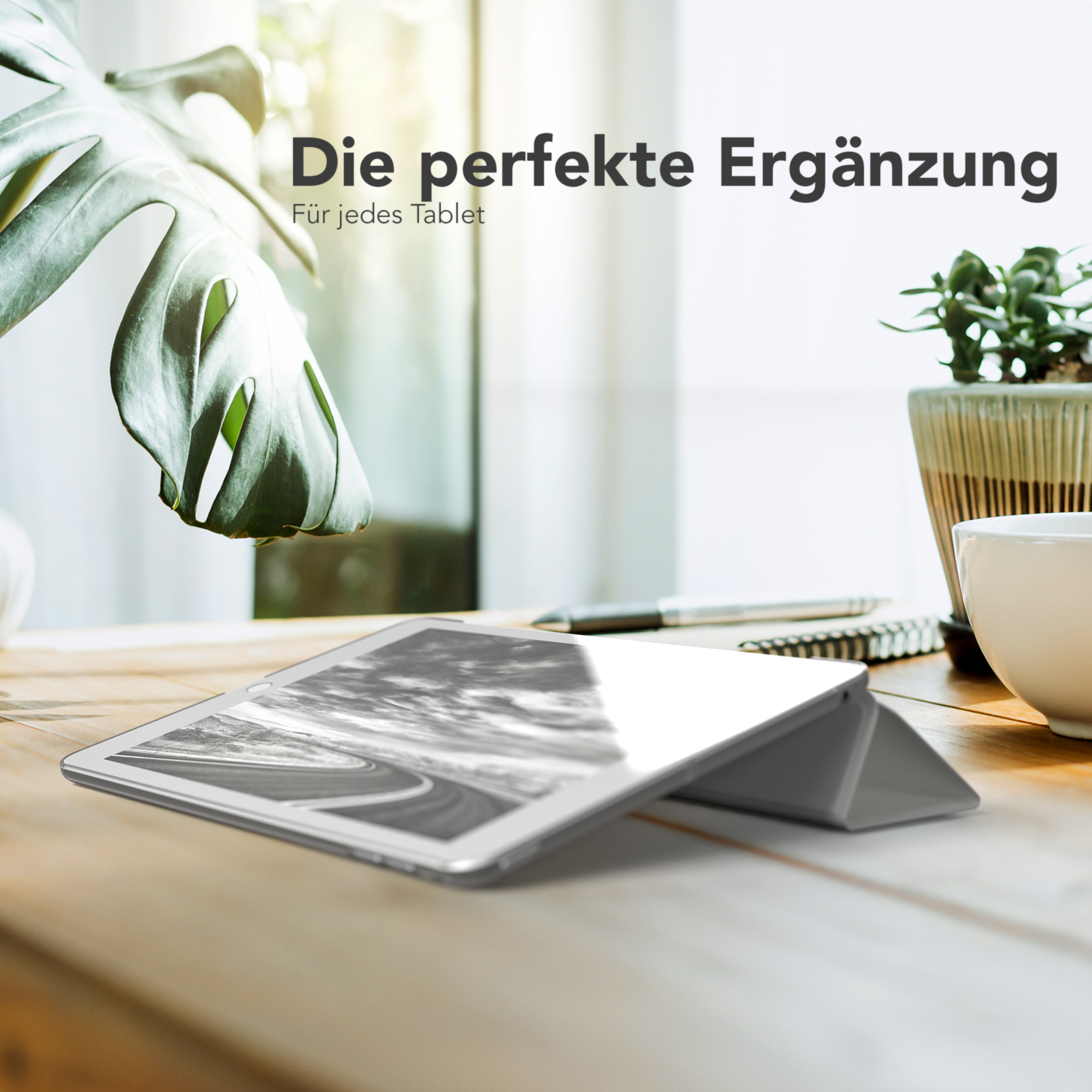 Ein Tablet in einer Hülle auf einem Holztisch mit einem Fenster im Hintergrund.