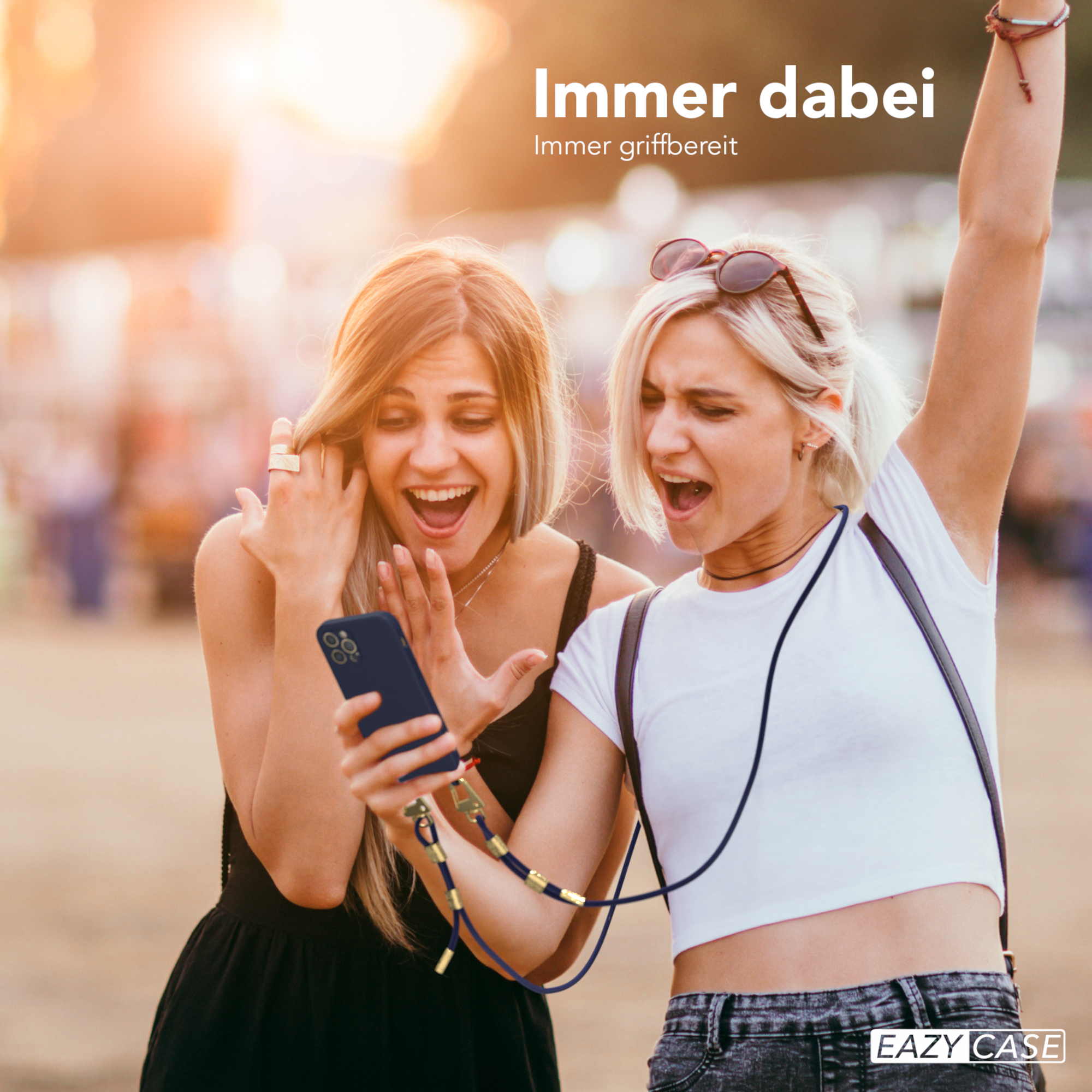 Zwei Frauen schauen auf Telefon mit Band. Eine hebt die Arme.