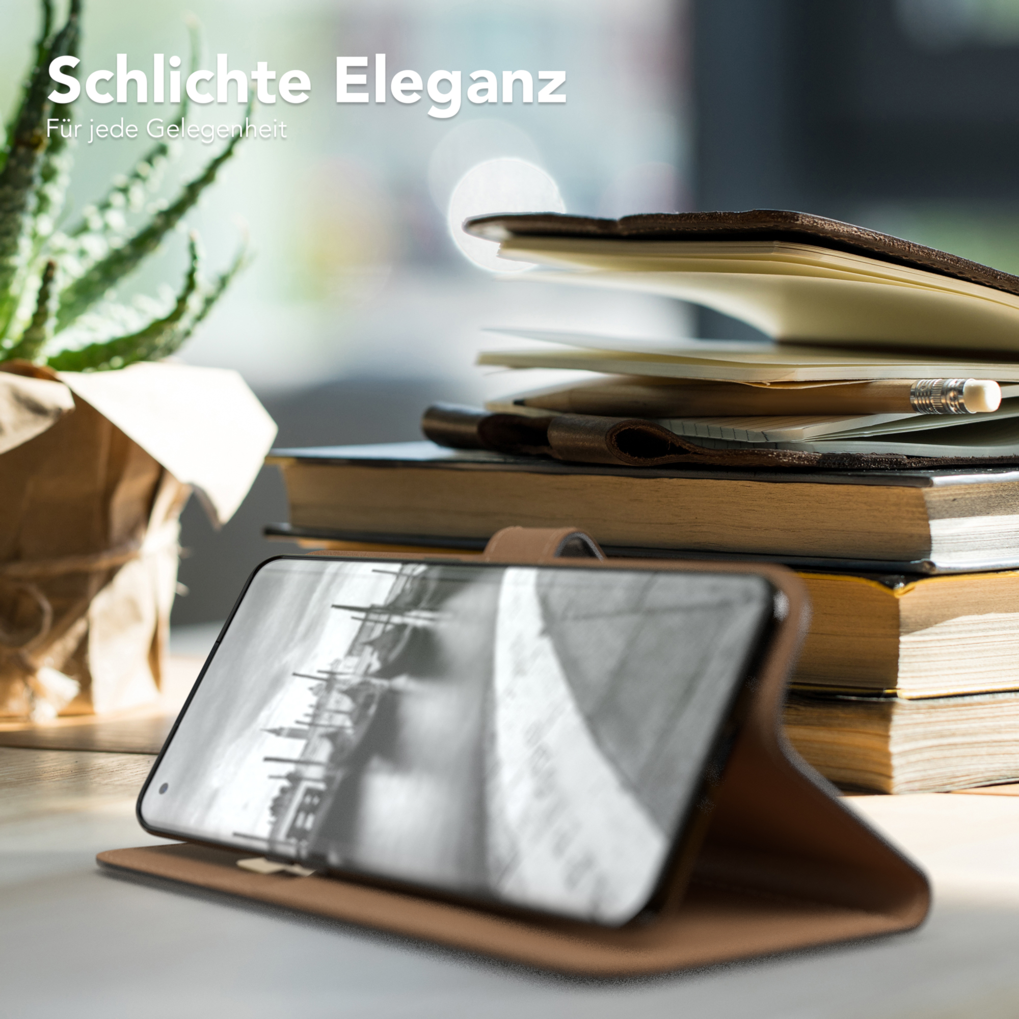 Telefon in brauner Hülle, auf einem Schreibtisch. Bücher und Pflanze im Hintergrund.