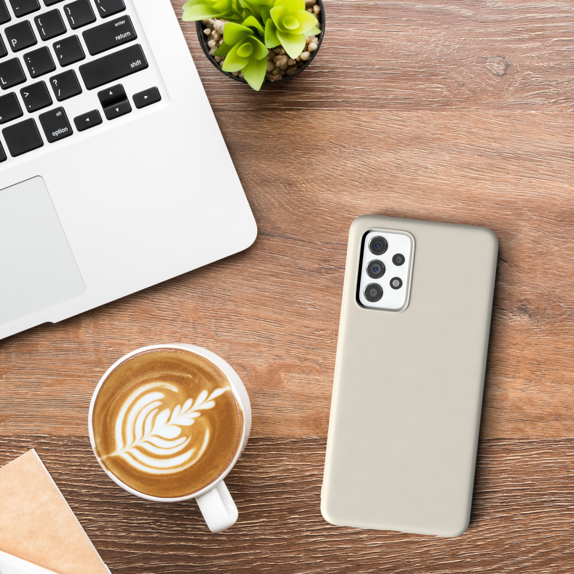 Laptop, Kaffee, Handyhülle und Pflanze auf einem Holztisch. Draufsicht.
