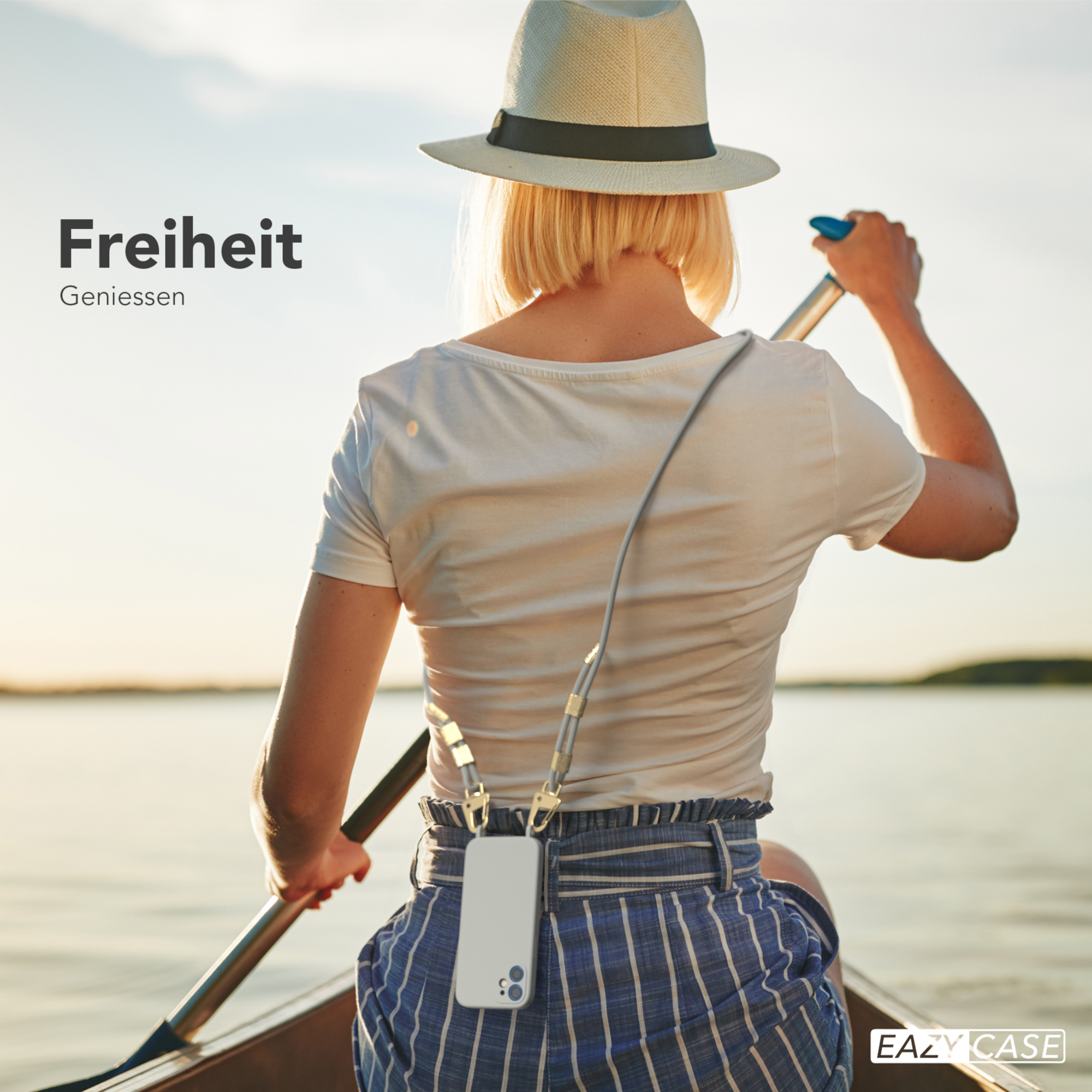 Frau rudert im Boot, hält Telefon mit Schlüsselband, Text: Freiheit.