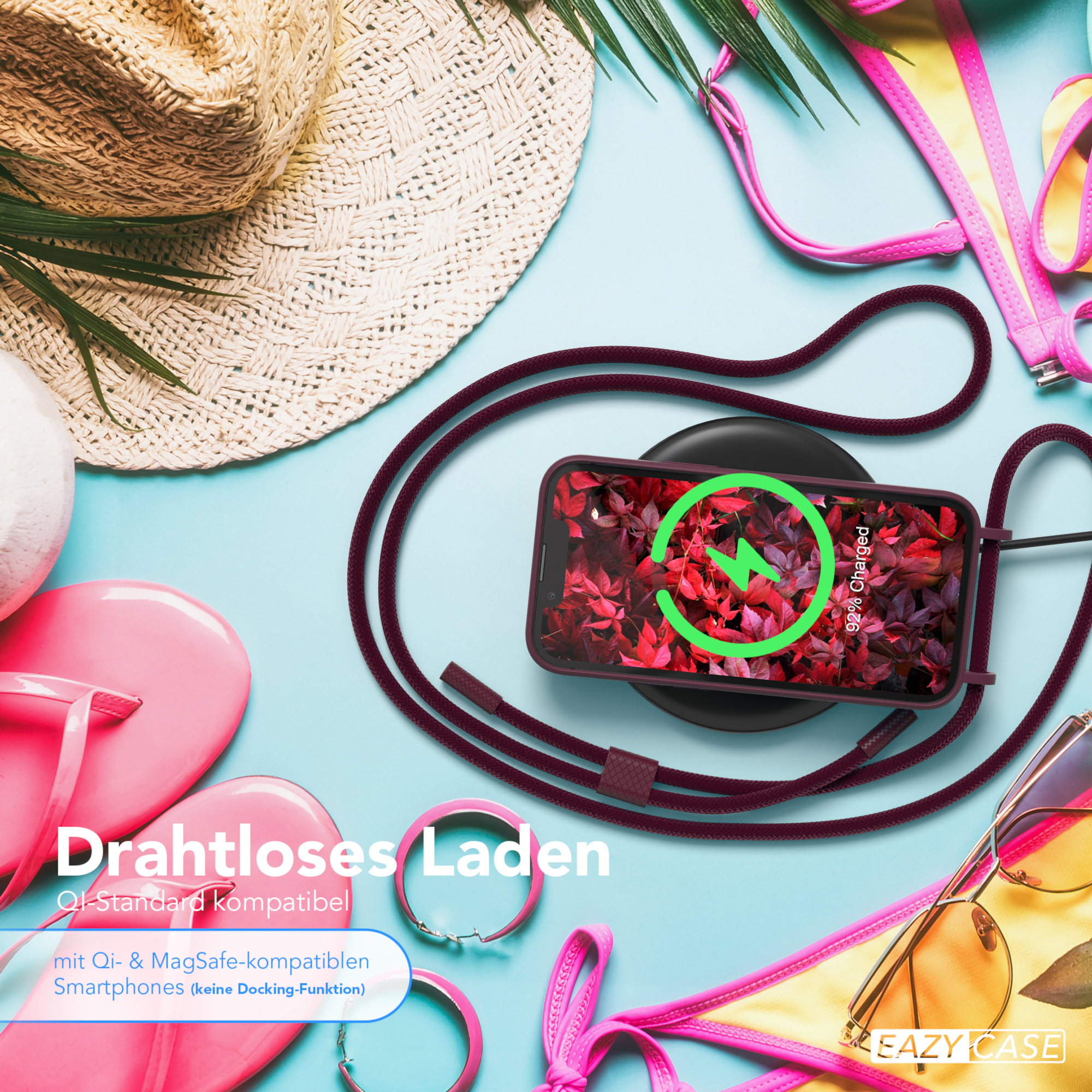 Telefon auf kabellosem Ladegerät, pinkfarbene Handyhülle, Sonnenbrille, Bikini-Oberteil auf blauer Oberfläche.