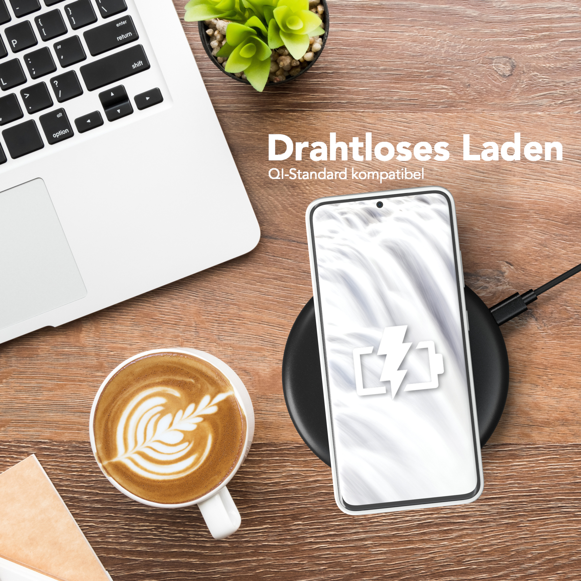 Kabelloses Ladegerät, Telefon lädt, Laptop, Kaffee. Alles auf einem Holztisch. Das Telefon zeigt ein Batteriesymbol.