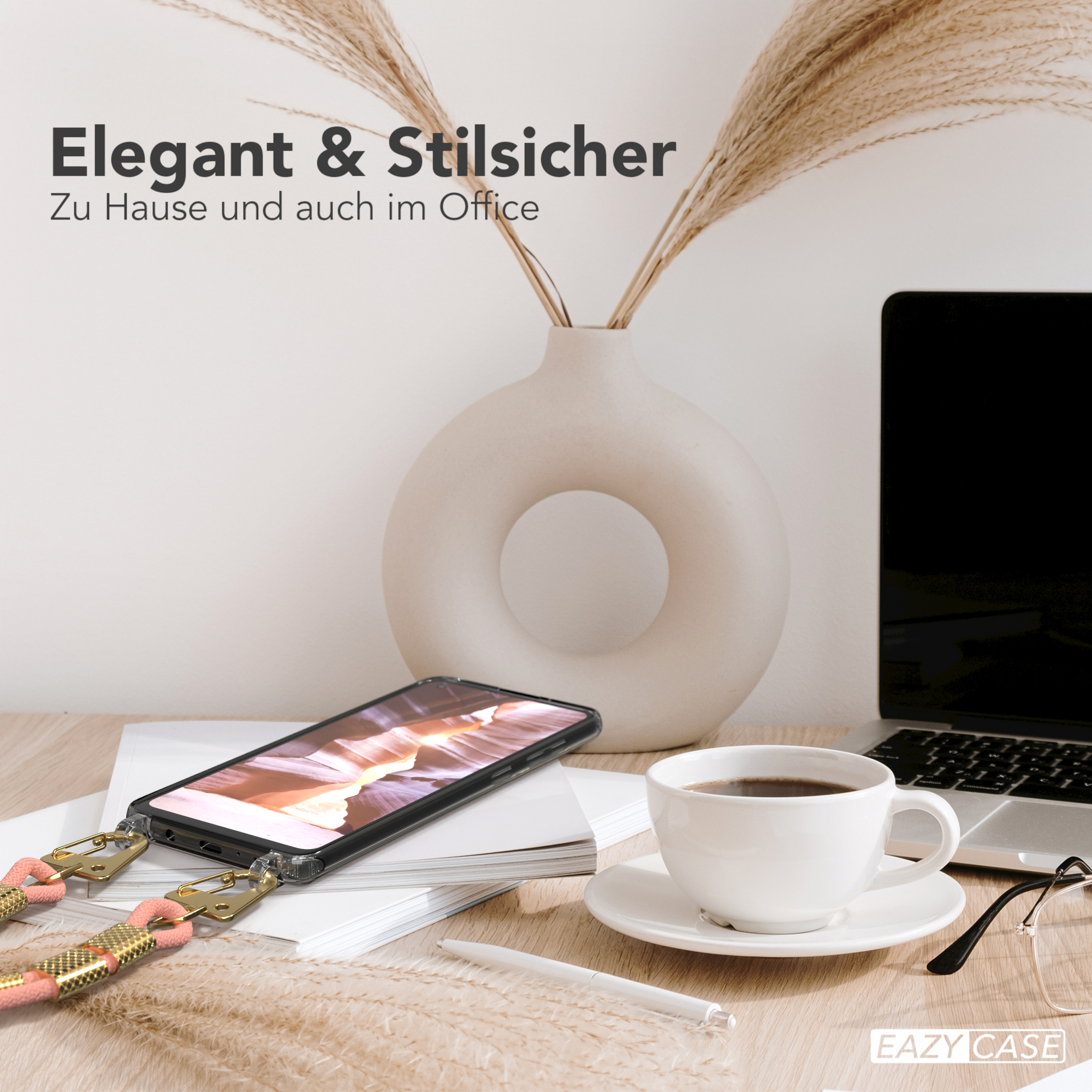 Telefon auf einem Schreibtisch neben einer Kaffeetasse und einer Vase mit Pampasgras.