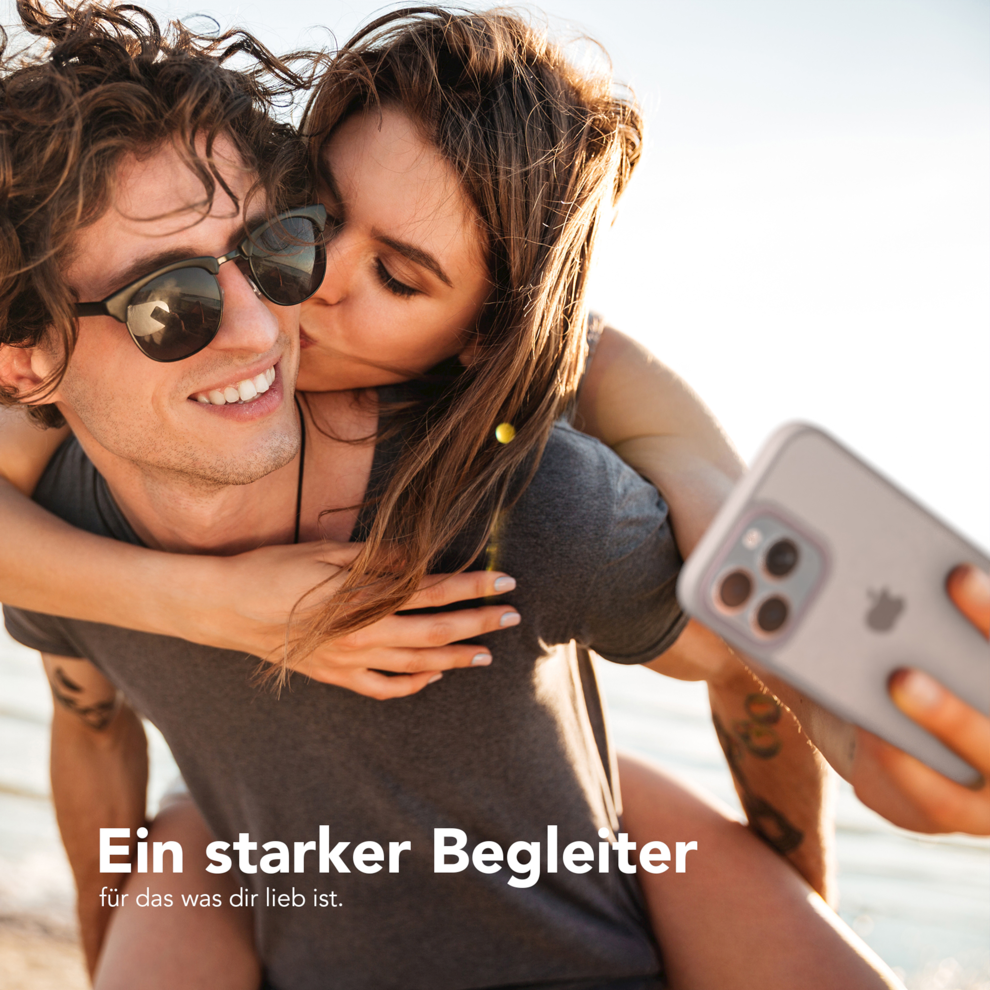 Frau küsst Mann auf die Wange, während sie ein Selfie mit dem Telefon macht.