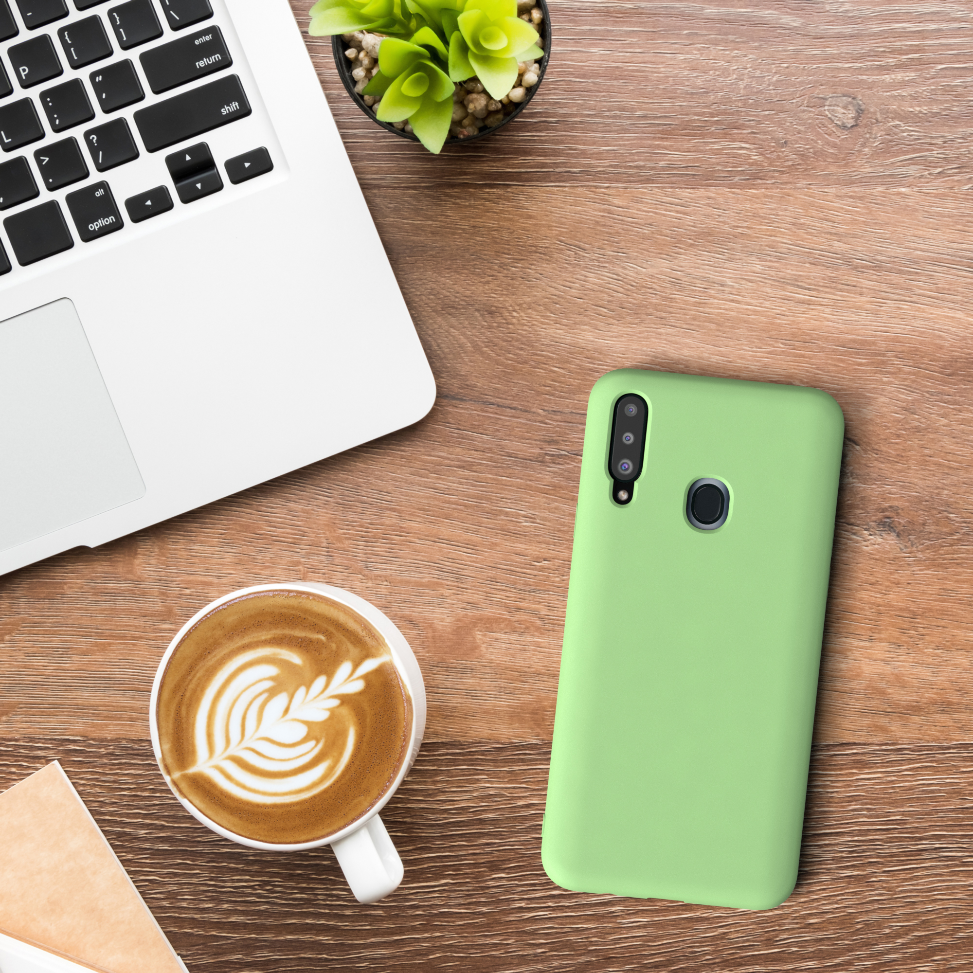 Eine grüne Handyhülle, Laptop, Kaffee und Pflanze auf einem Holzschreibtisch.