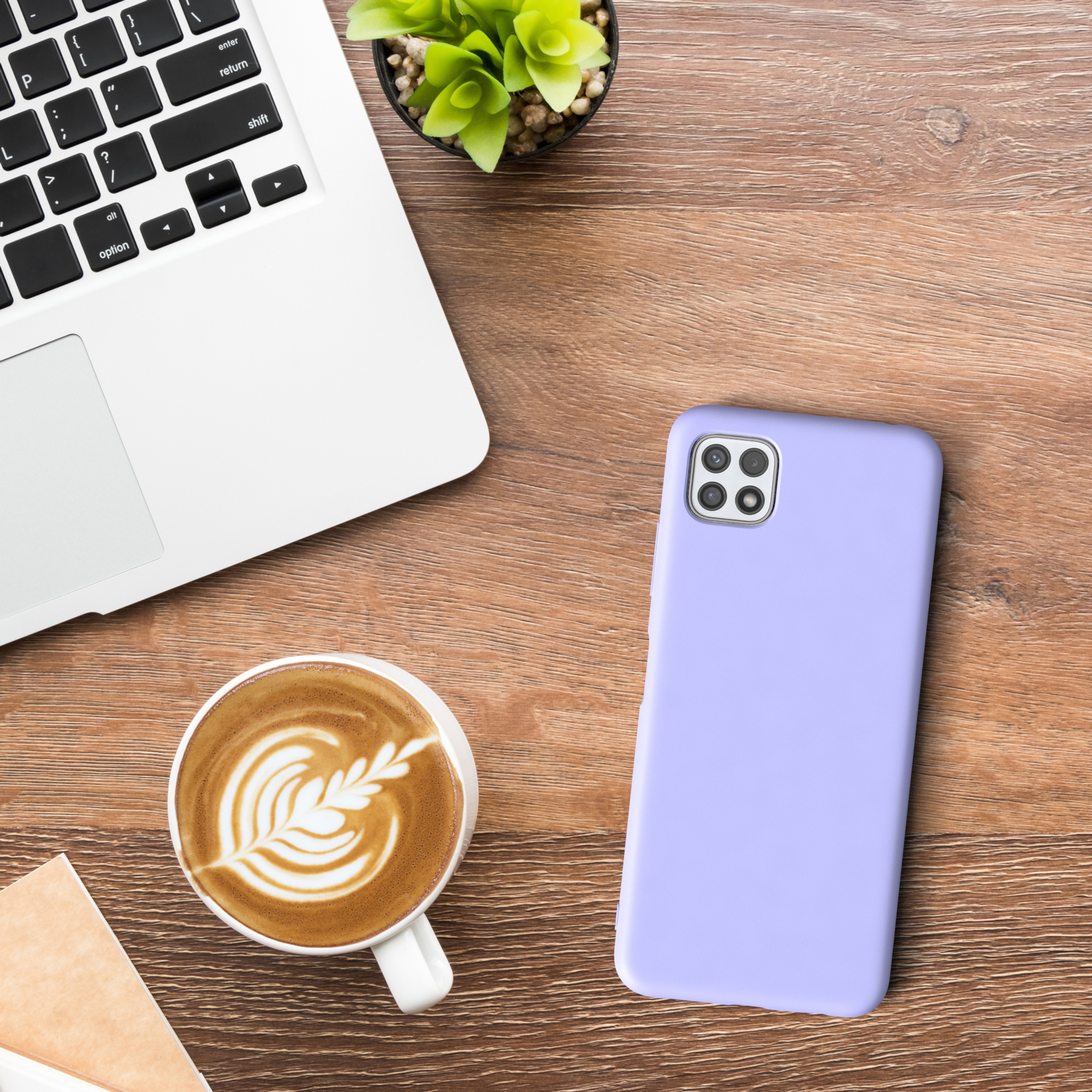 Draufsicht auf einen Schreibtisch mit Laptop, Kaffeetasse und lavendelfarbener Handyhülle.