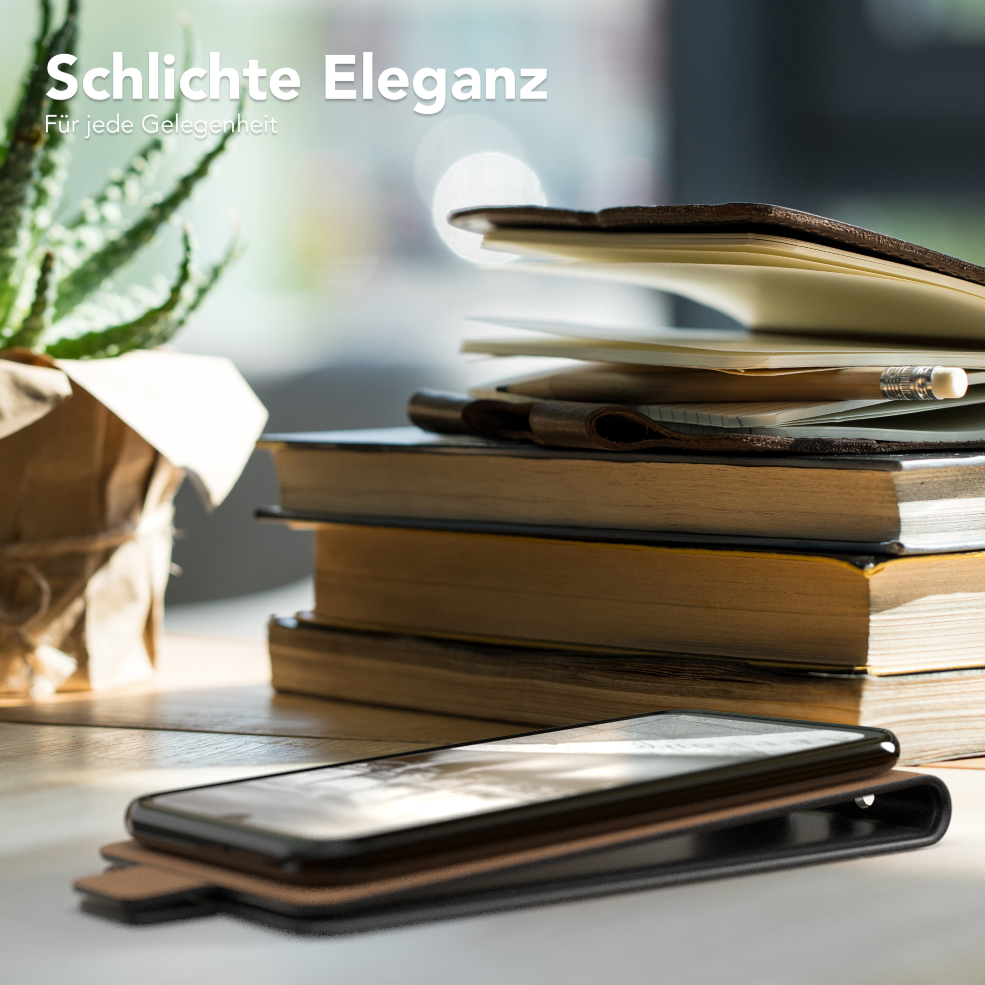 Handyhülle neben Büchern und einer Pflanze auf einem Holztisch. Ein Stift ist sichtbar. Die Szene ist gut beleuchtet.