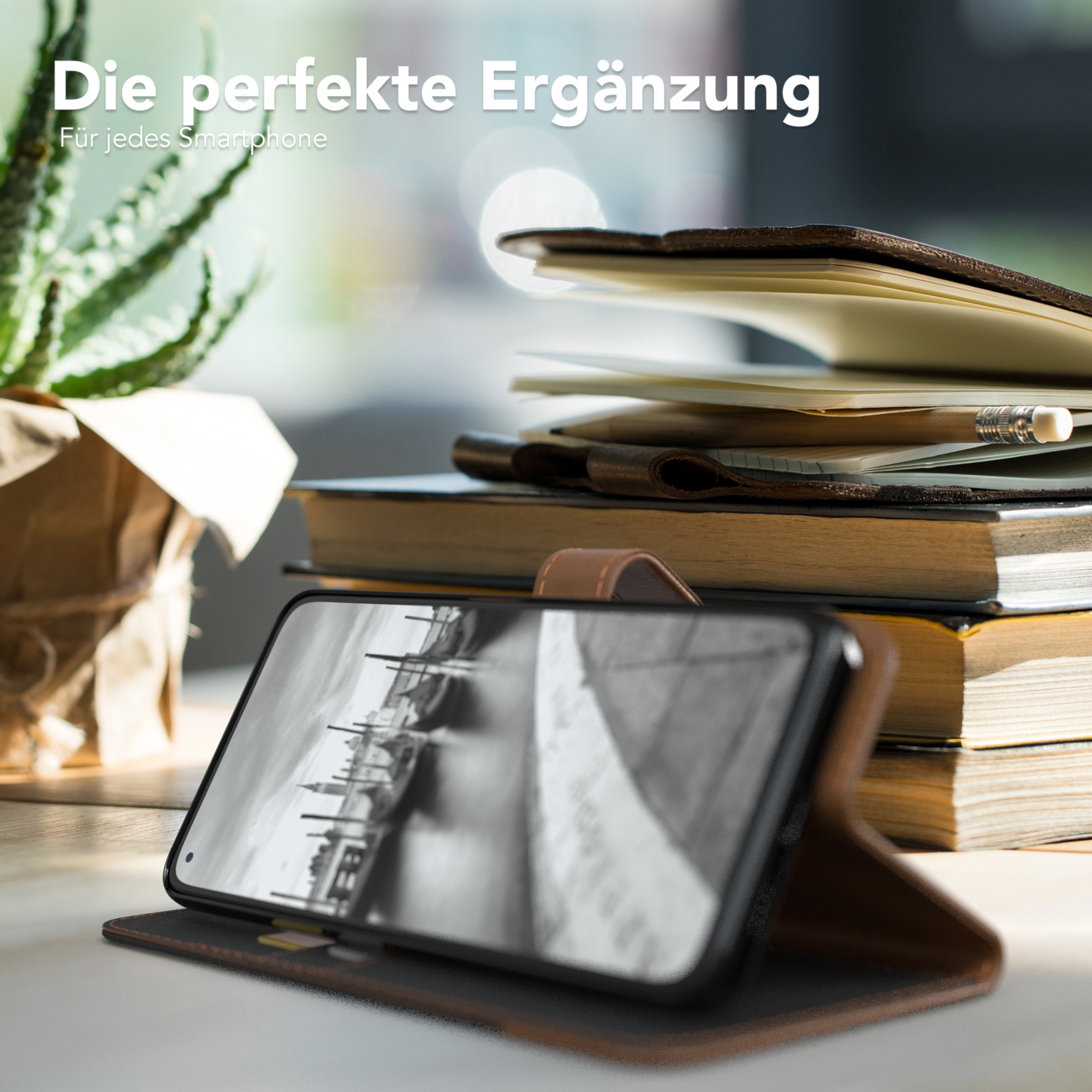 Telefon in einer Hülle auf einem Schreibtisch mit Büchern und einer Pflanze, Venedig.