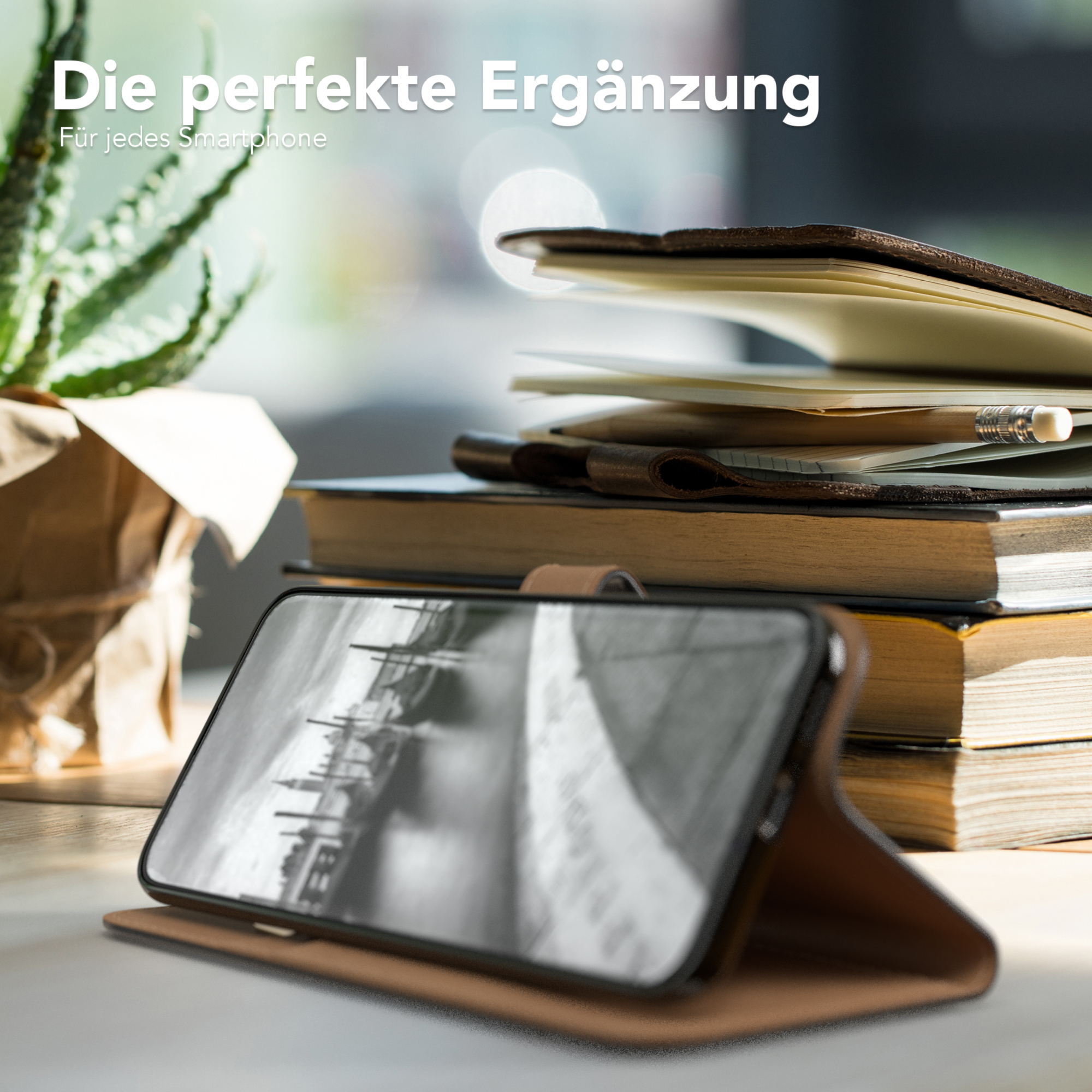 Ein Telefon in einer Hülle, platziert auf einem Tisch mit Büchern und einer Pflanze.