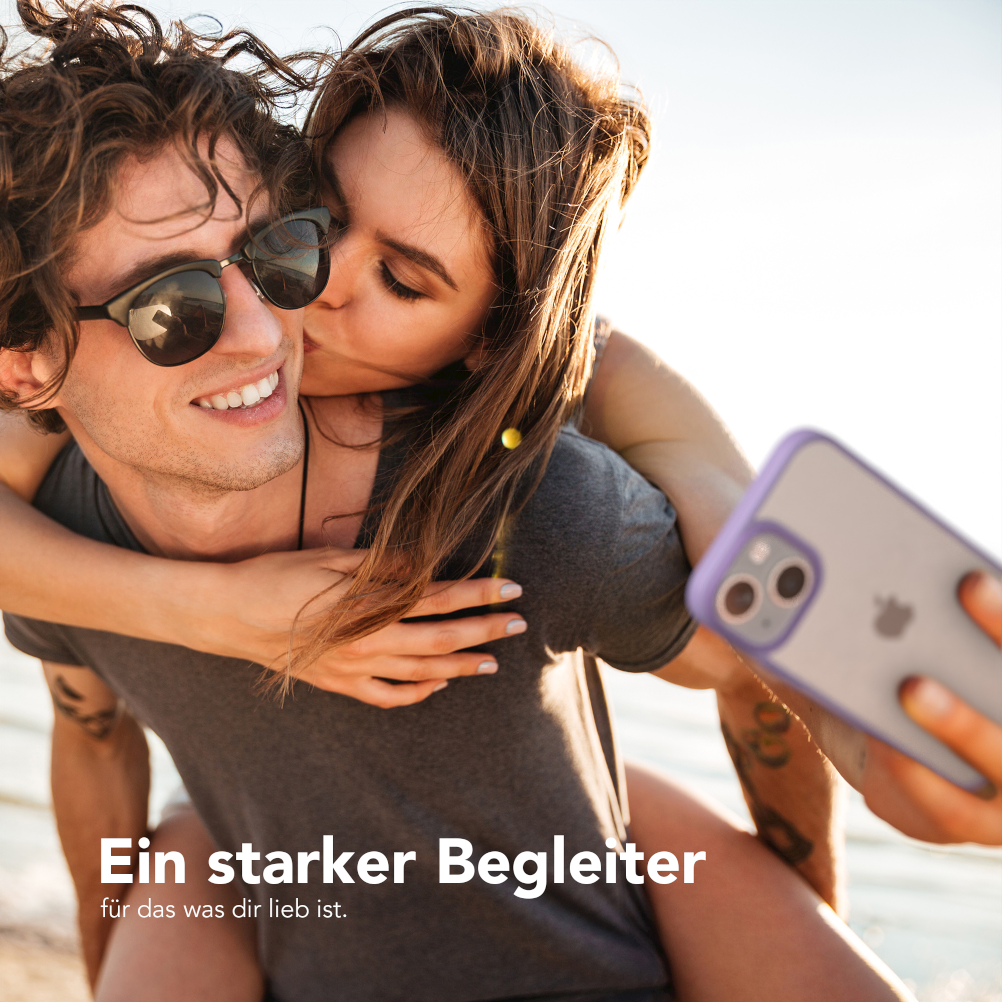 Ein Paar macht ein Selfie. Frau küsst Mann auf die Wange, beide lächeln, halten ein Telefon.